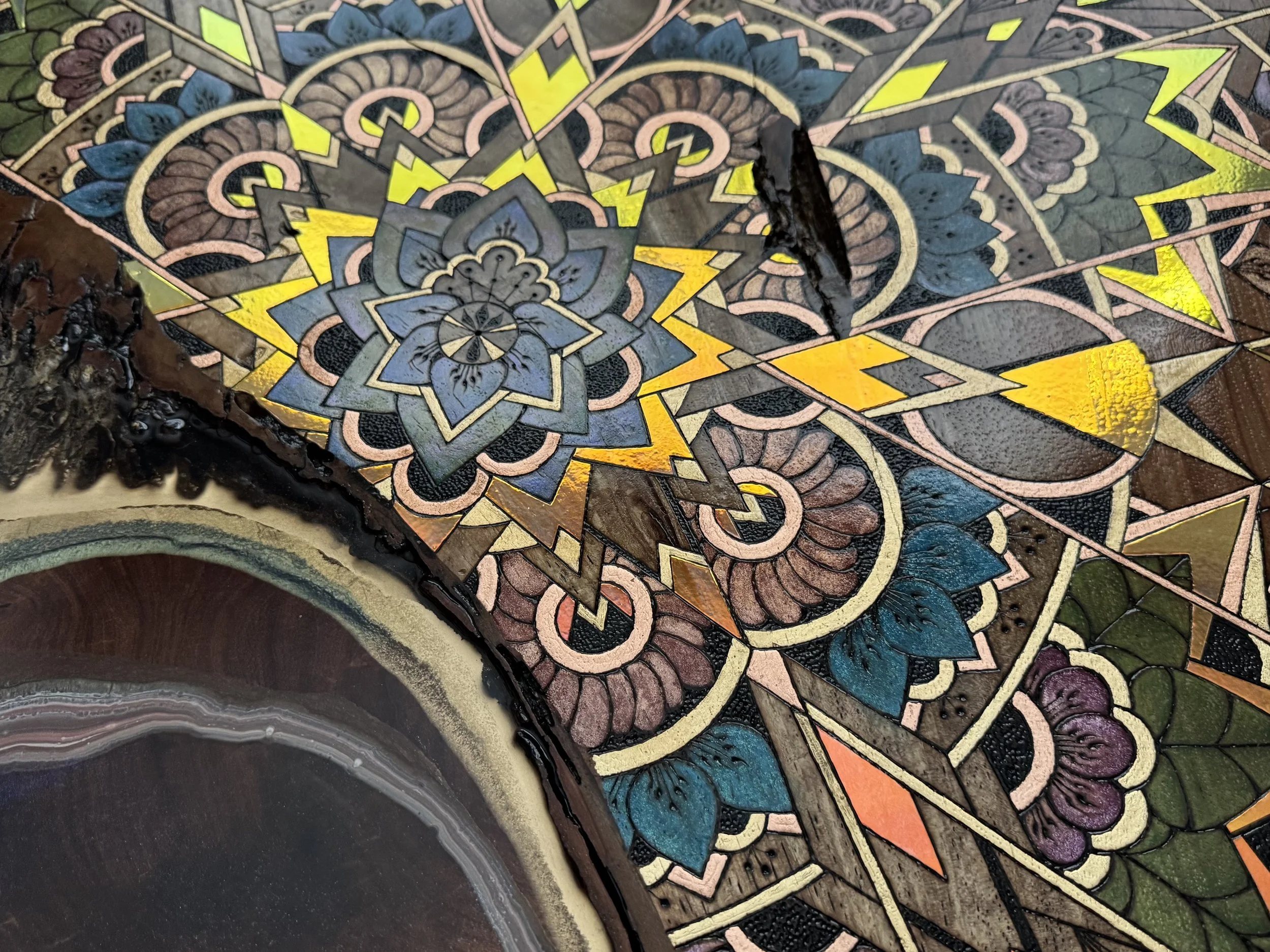 Sacred floral mandala carved into wood and accented with pigment, glitter, and metallic leaf. Resin river adds movement and lightplay.