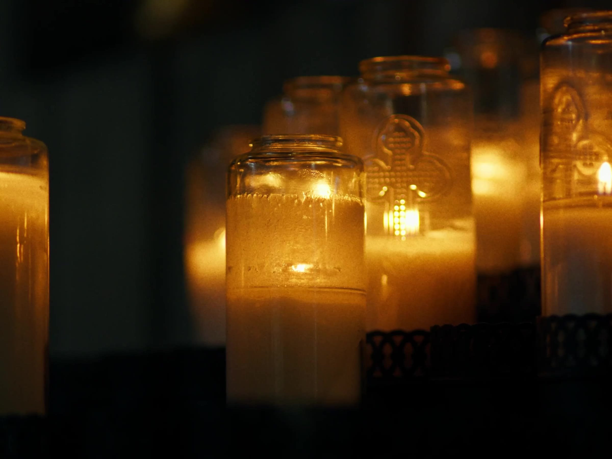 Votive candles glowing in the Newman Hall chapel. Photo by @reagancalaguasfilm