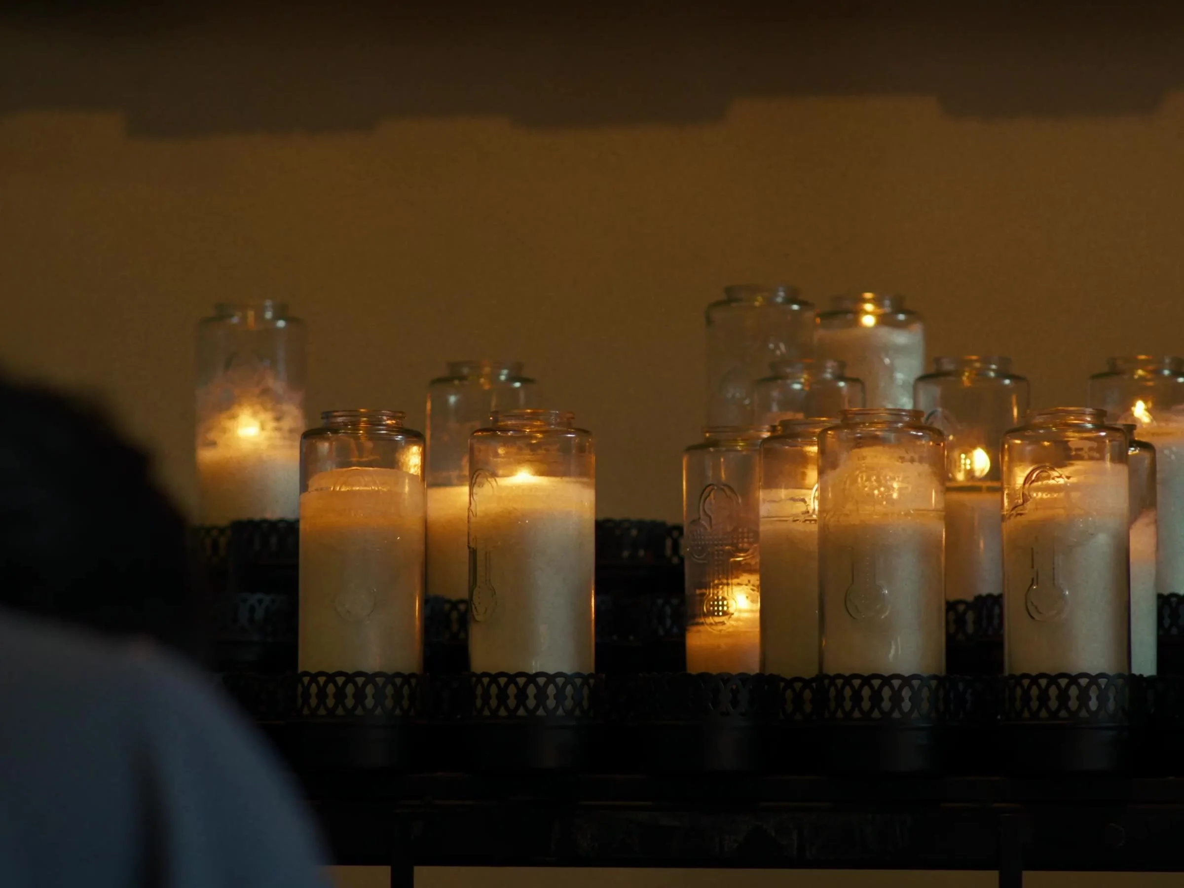 A parishioner praying before votive candles in the Newman Hall chapel. Photo by @reagancalaguasfilm