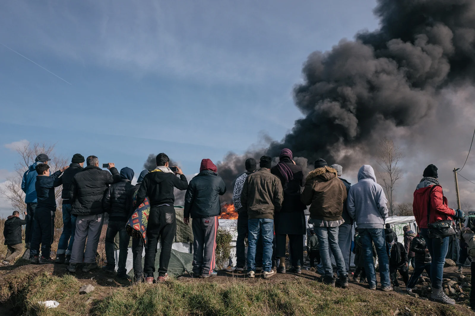 People watch as a shelter burns during the eviction of the southern part of the "Jungle" camp in March 2016. Photograph: Rob Pinney for Point.51