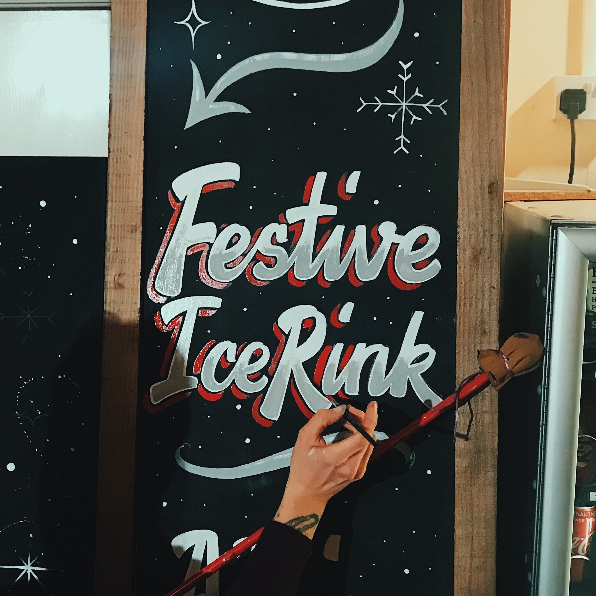 Painting of a script style 'Festive Ice Rink'