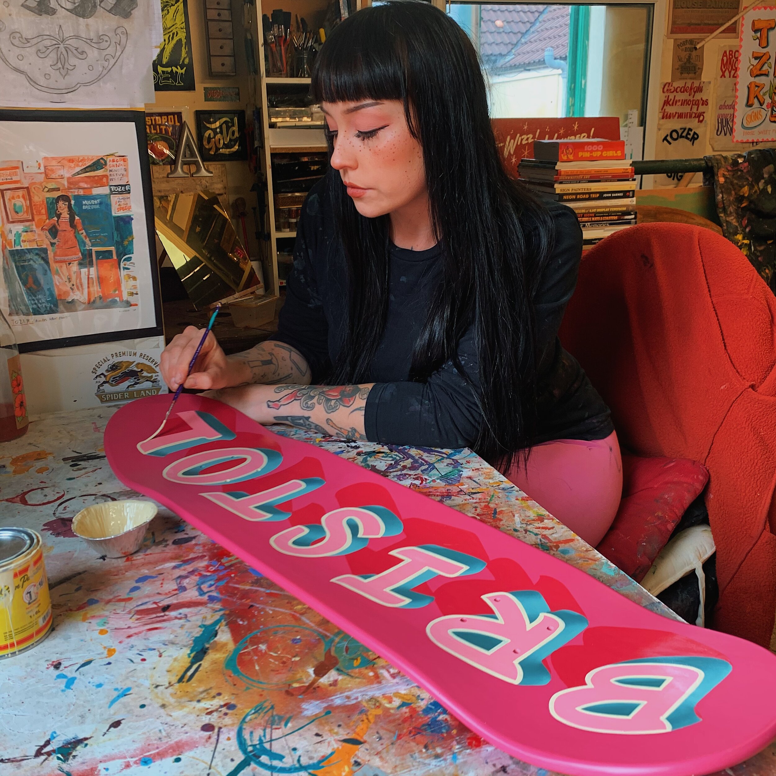 Tozer Signs hand-painting a skate deck with the word 'Bristol'.