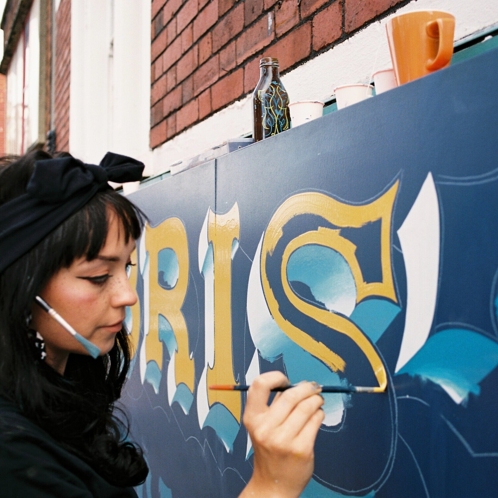 Female signwriter painting a fascia sign.