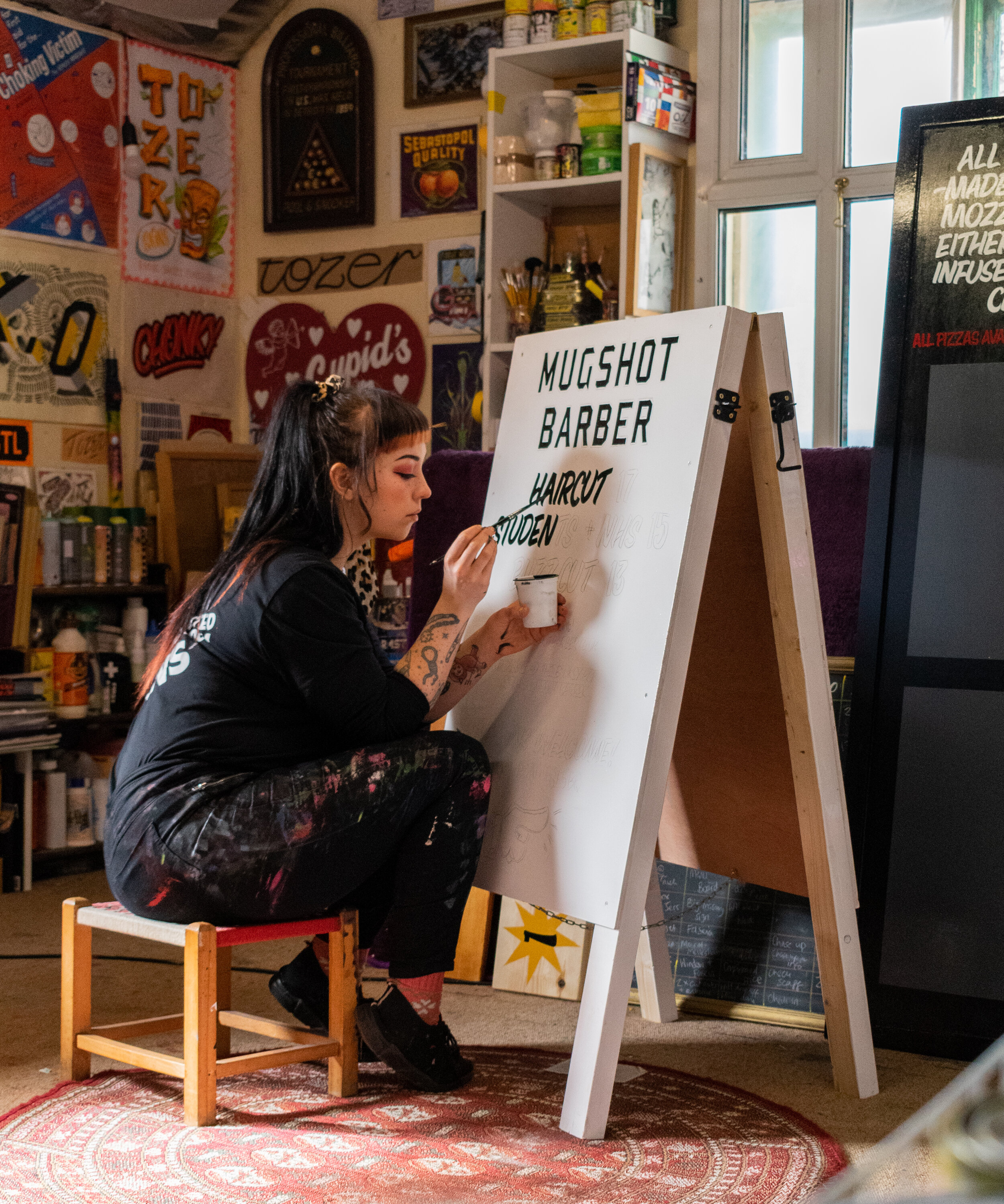 Woman signpainter hand-painting a double-sided a-board.