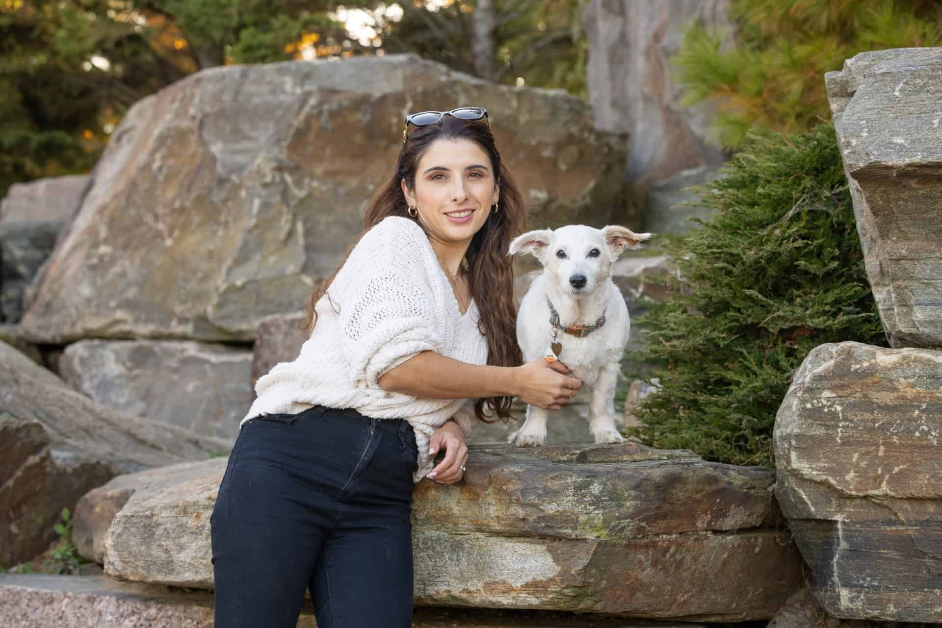 Woman and a small terrier dog leaning against rocks in a Toronto park