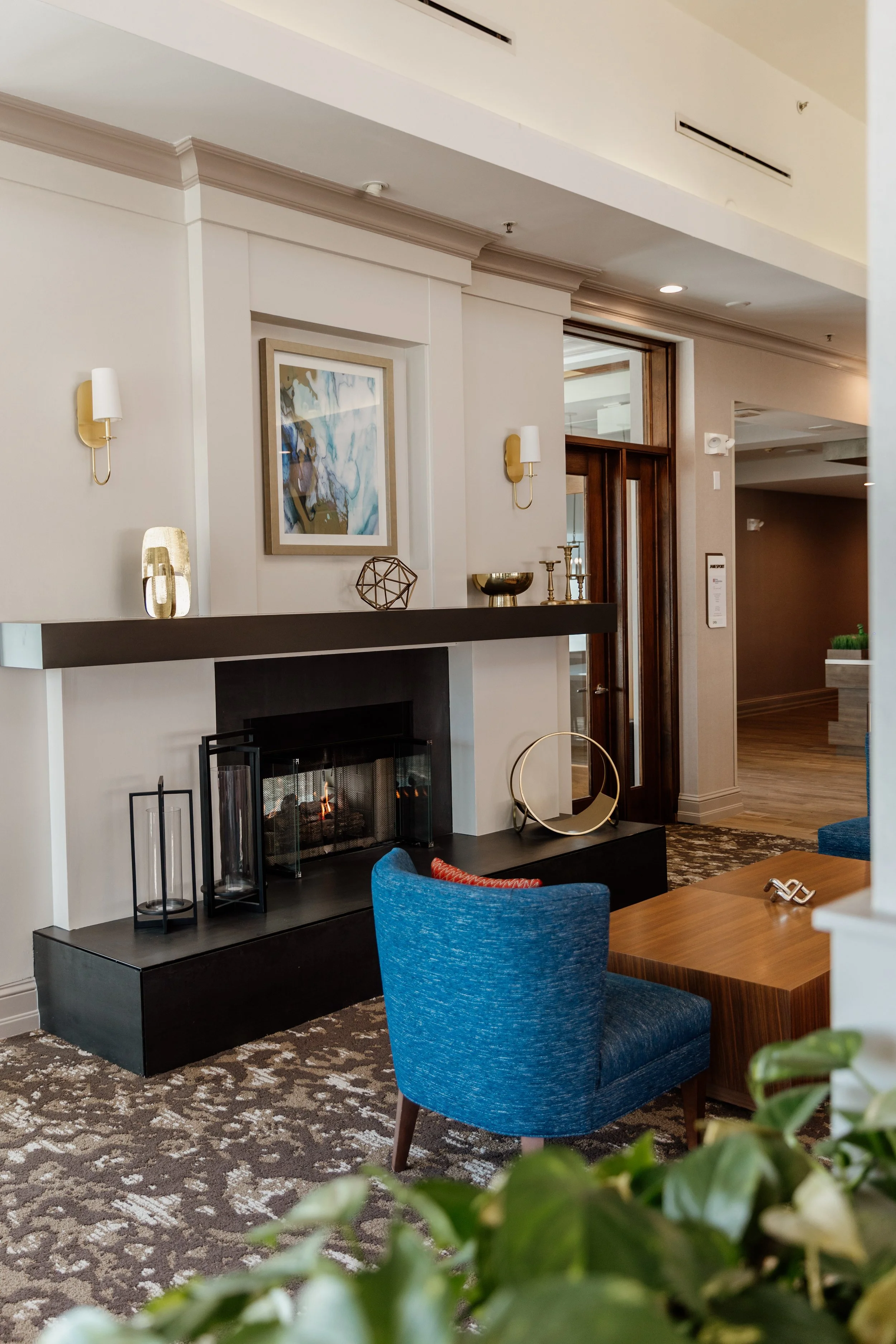 Living room with a fireplace, blue armchair, wooden coffee table, and decorative objects on the mantel and wall