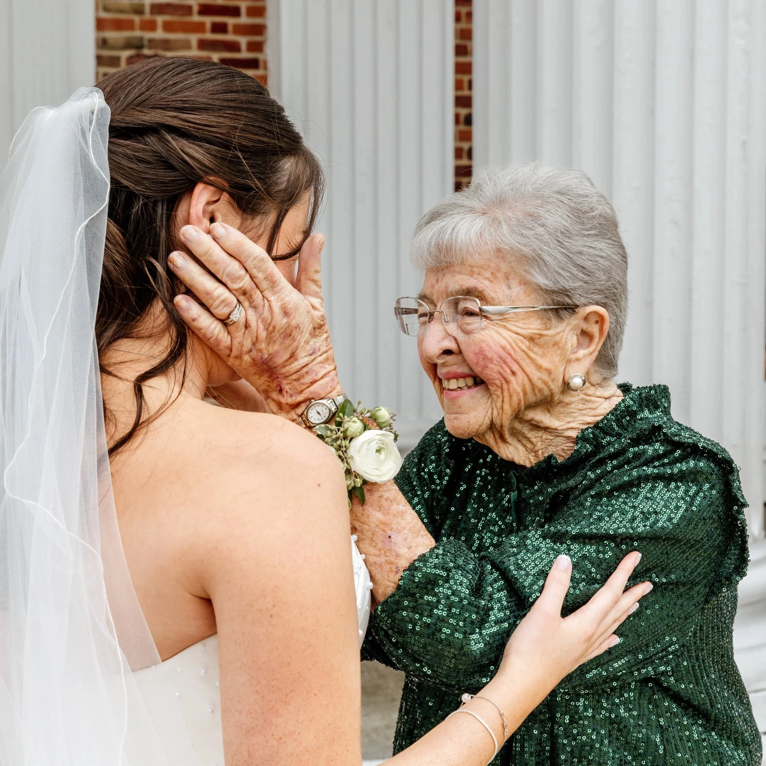 A candid, heartfelt moment between a grandmother and her granddaughter just after the church ceremony, full of happy tears and a love that needs no words.