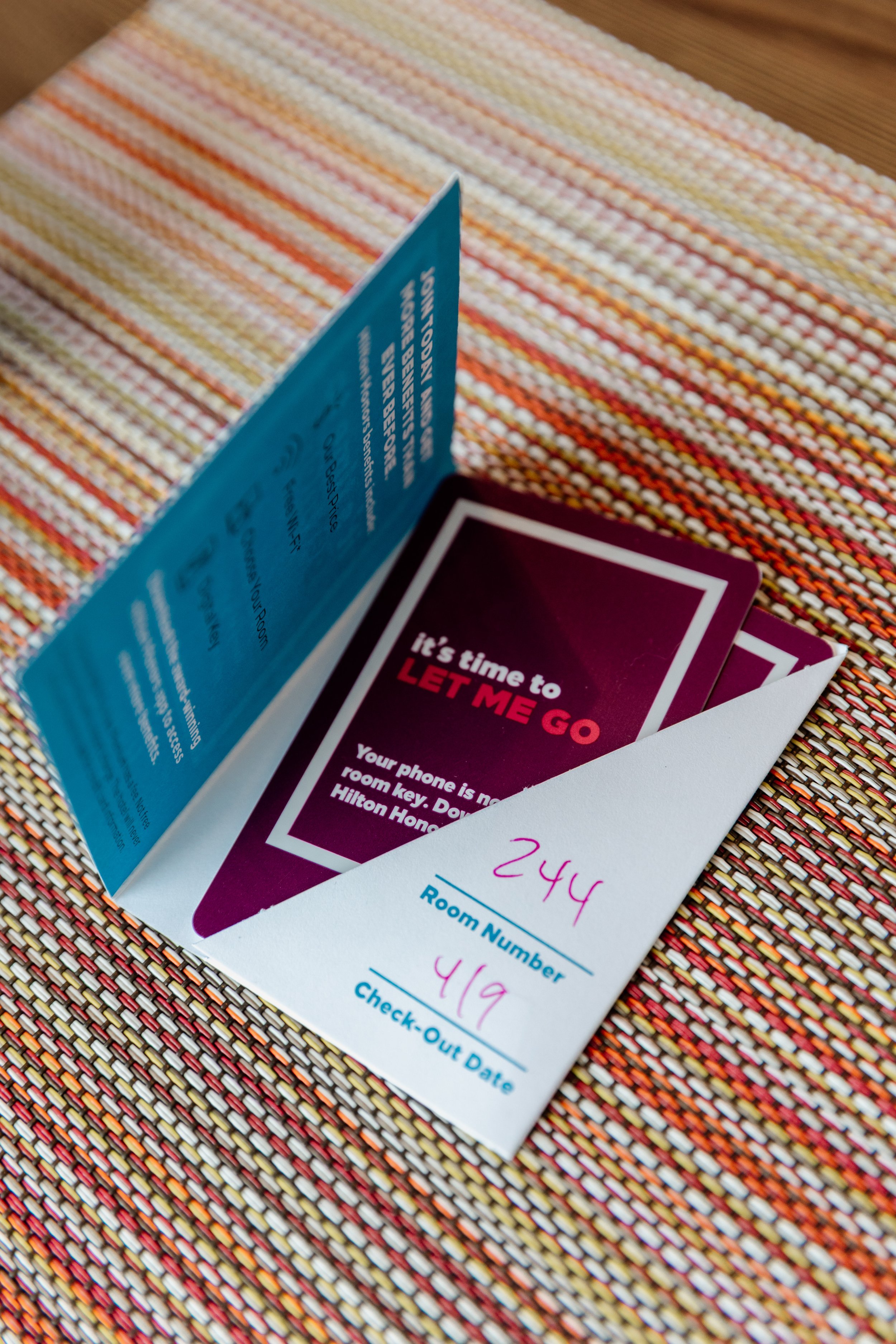 Hotel room key card with room number 244 and check-out date 4/19, placed on a colorful woven tablecloth.