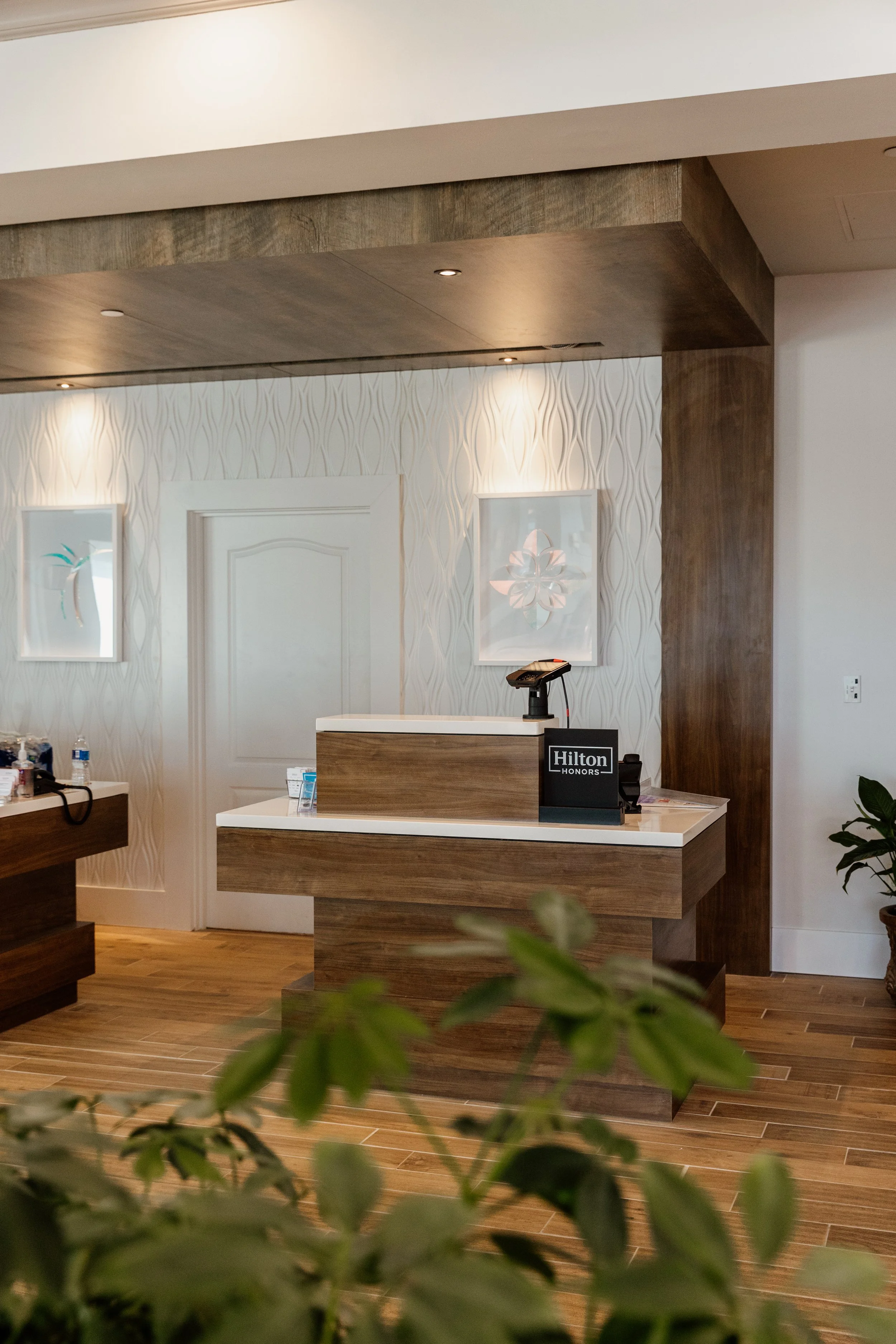 Hilton hotel front desk with a wooden counter, a checkout scanner, and a sign that says 'Hilton Honors'.