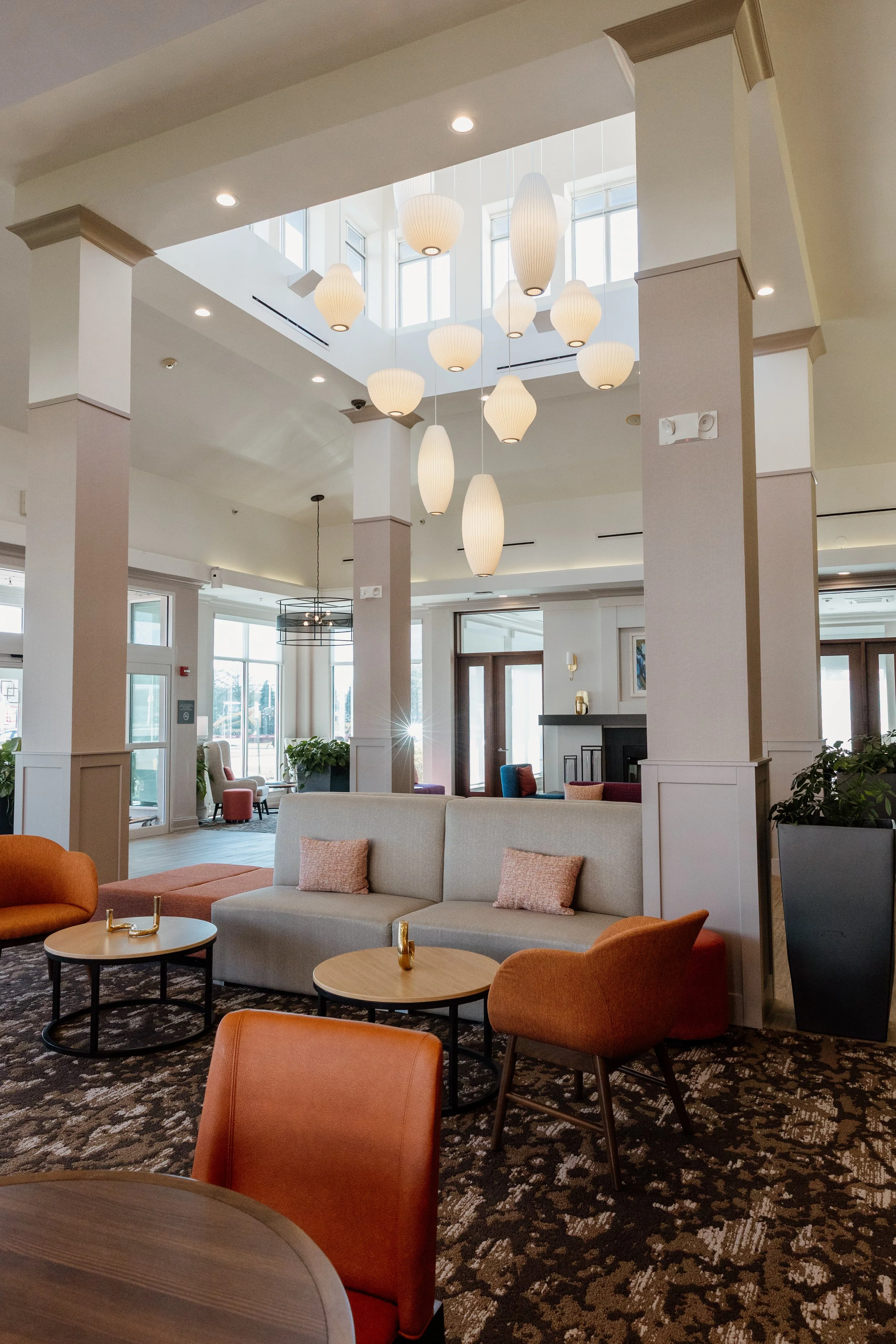 The Fork Restaurant at the Hilton Garden Inn in Riverhead, New York, a modern dining and lounge space with soaring ceilings, statement pendant lights, colorful seating, and contemporary art throughout.