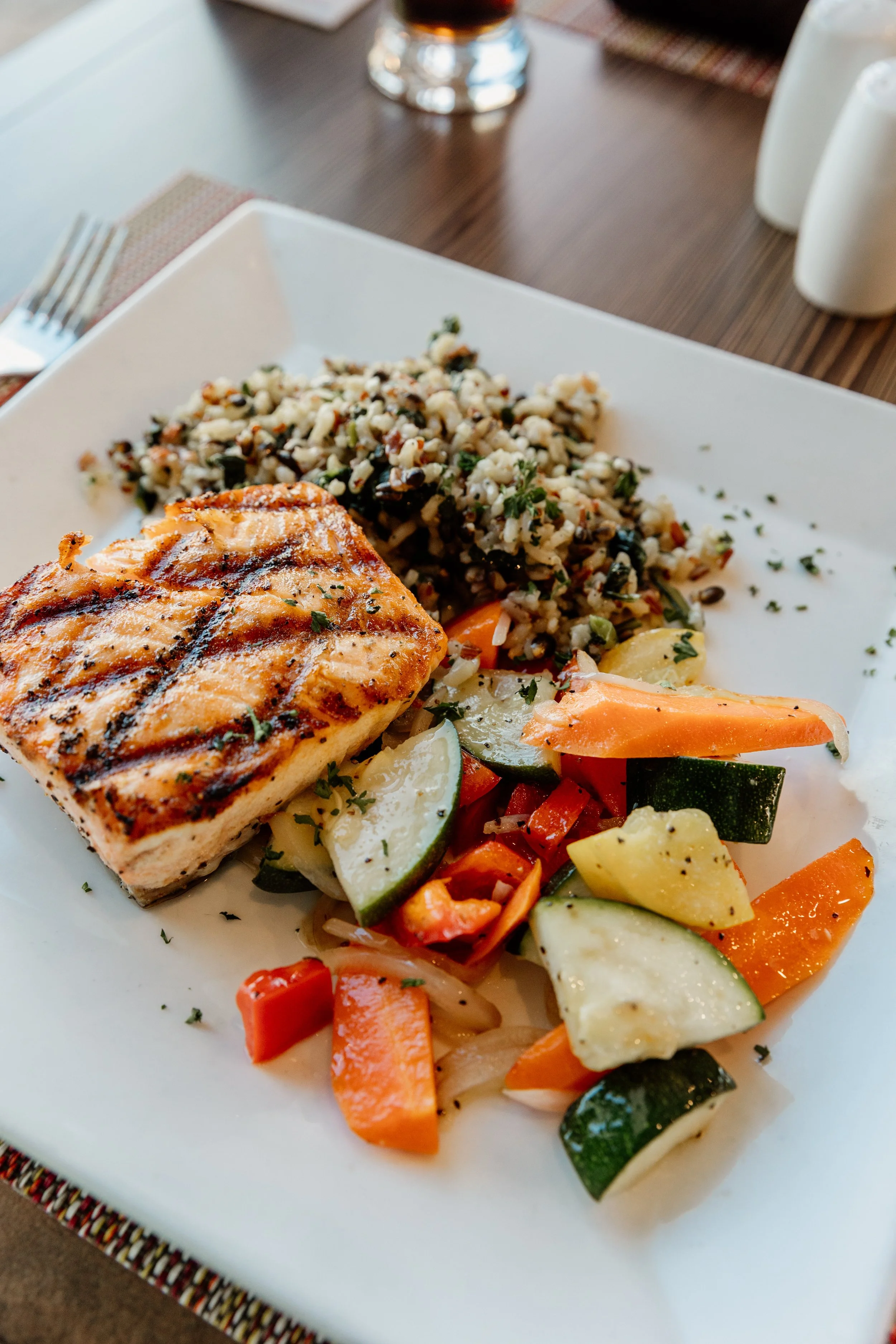 Grilled salmon fillet served with mixed grilled vegetables and a side of wild rice.