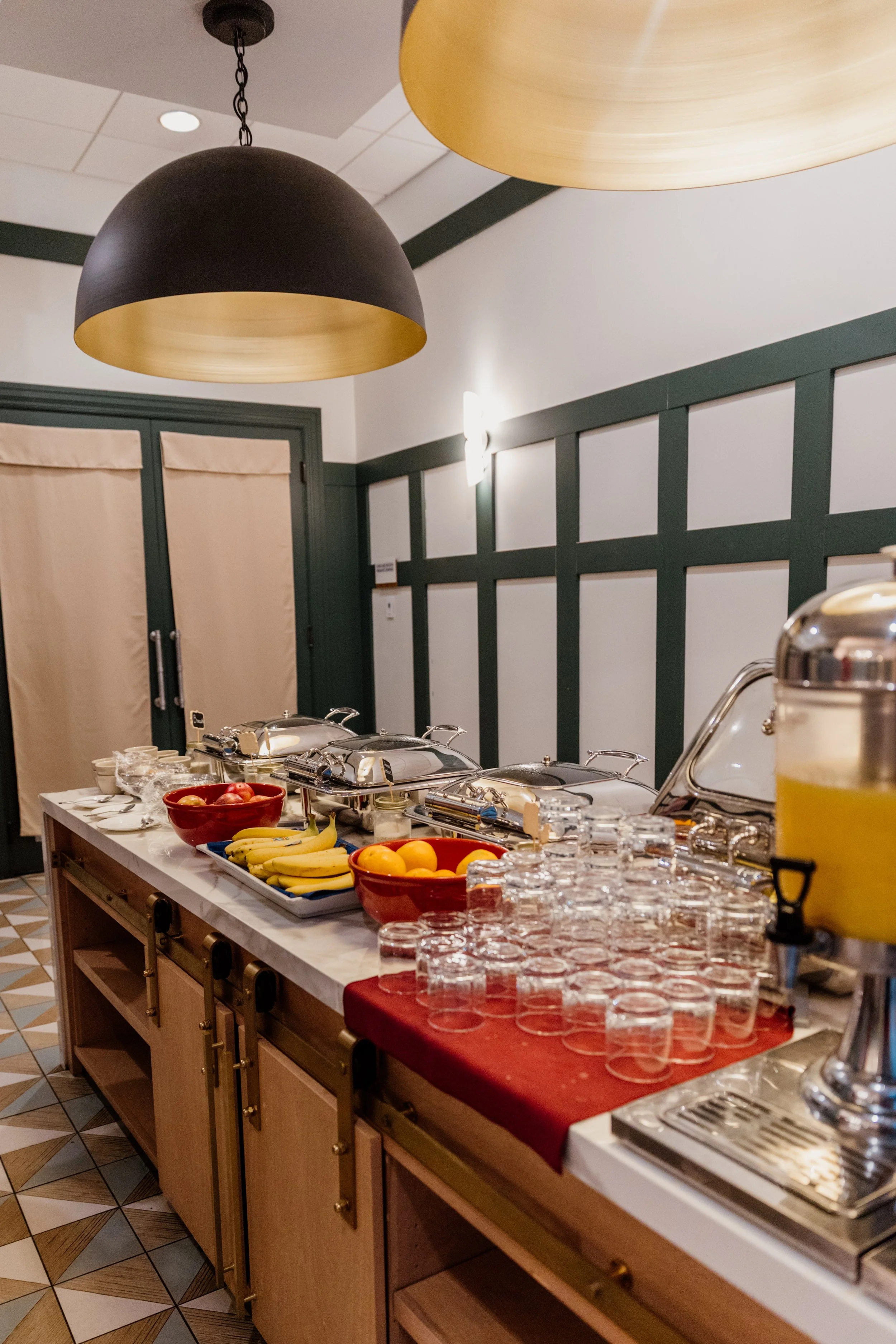 Buffet table with fruit, glasses, and chafing dishes at a restaurant.