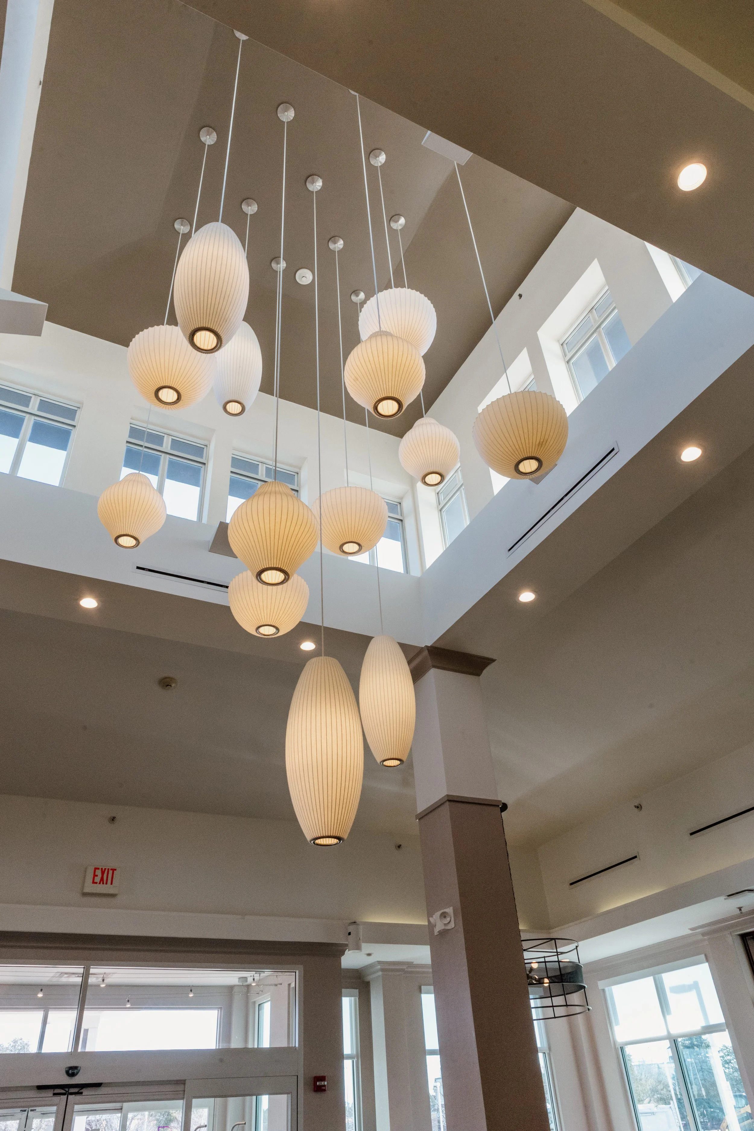 Interior of a modern space with pendant lights hanging from the ceiling and large windows letting in natural light.