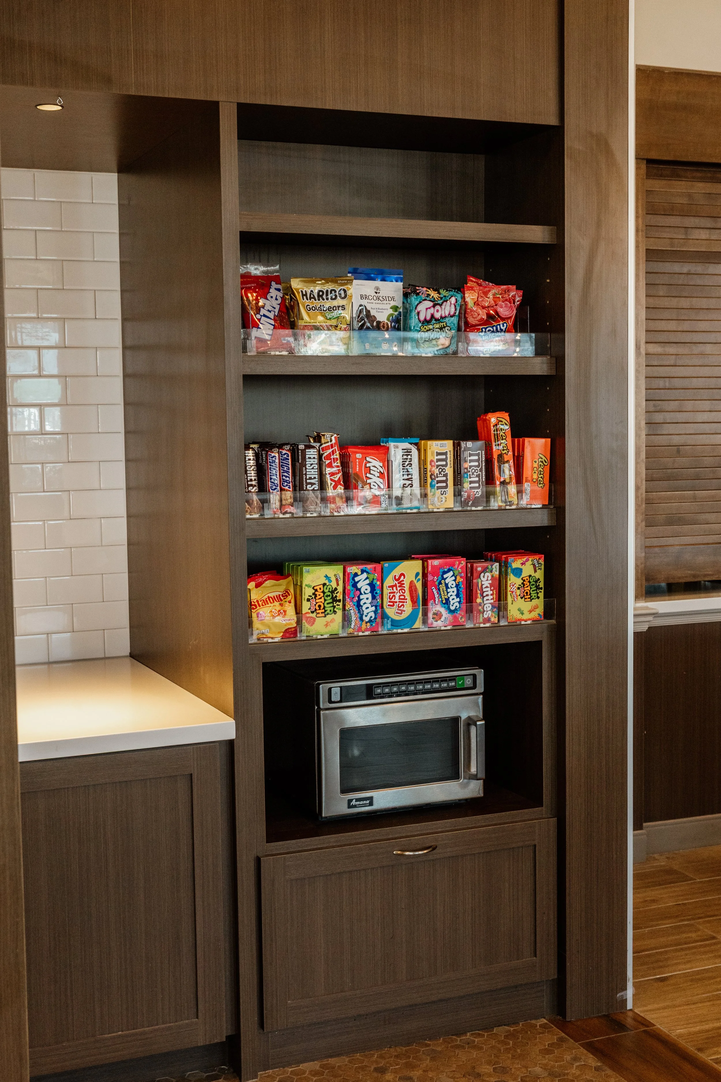 Snack shelf with various candy and a small microwave oven below.