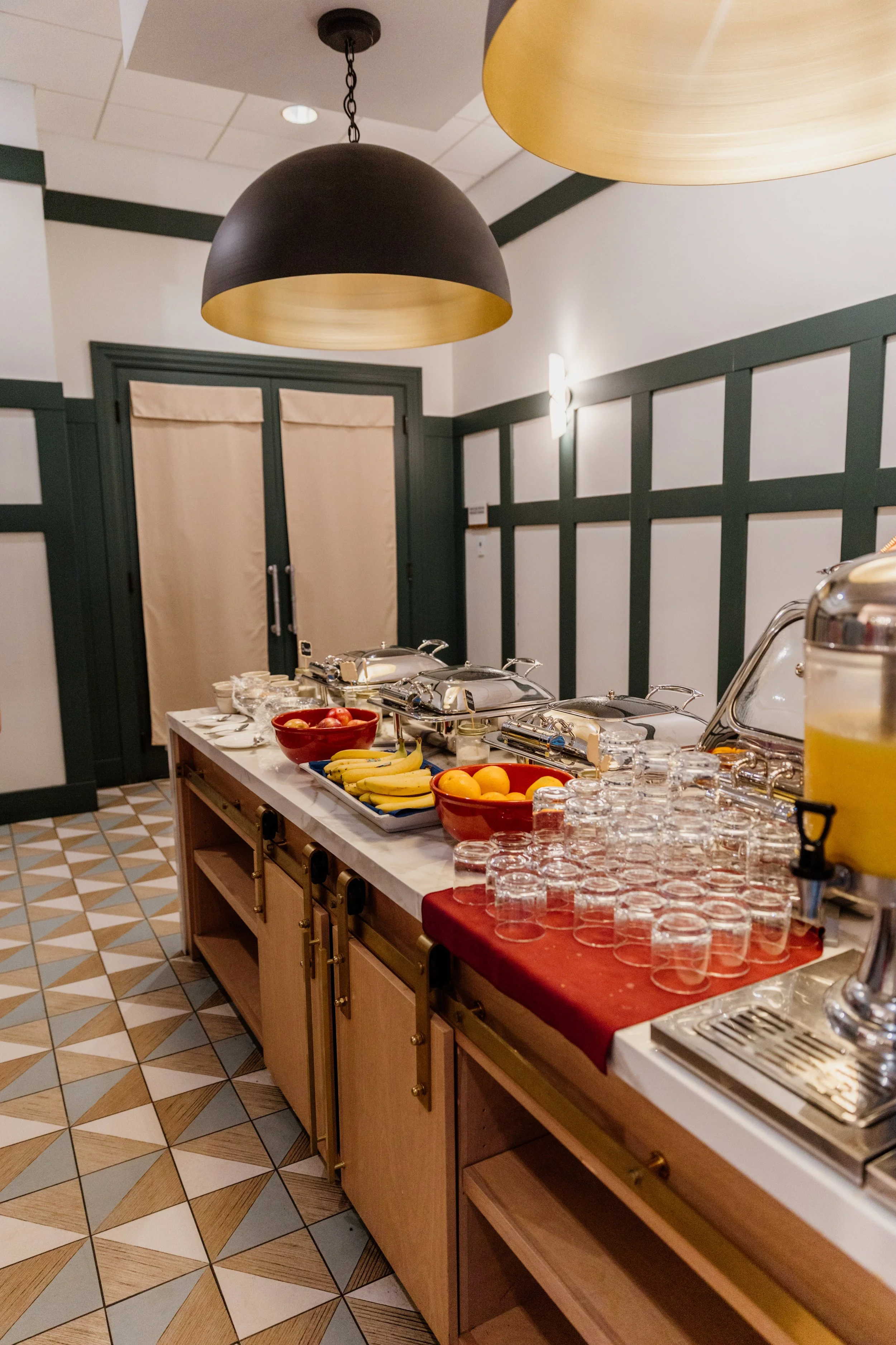 Buffet table with fruit, glassware, and chafing dishes in a restaurant setting.