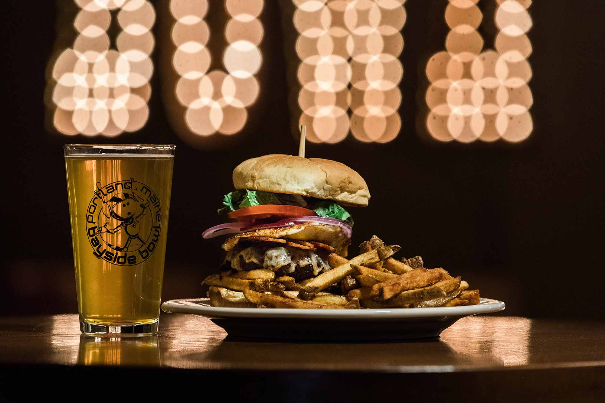 Burger and a beer with Bayside Bowl logo on glass