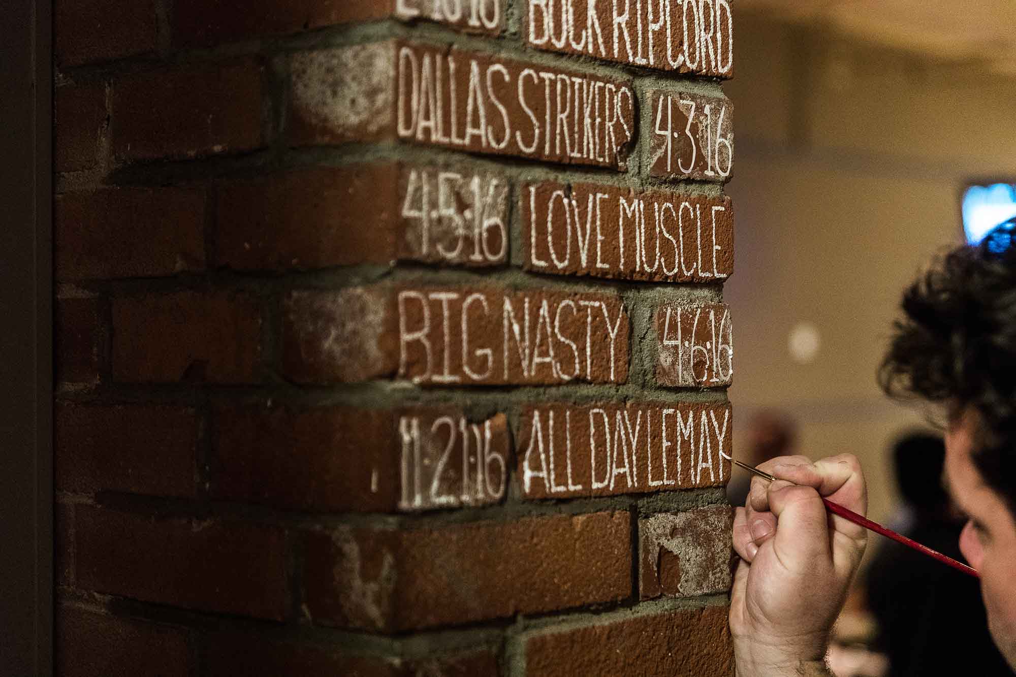 Person painting a 300 score on a brick wall at Bayside Bowl