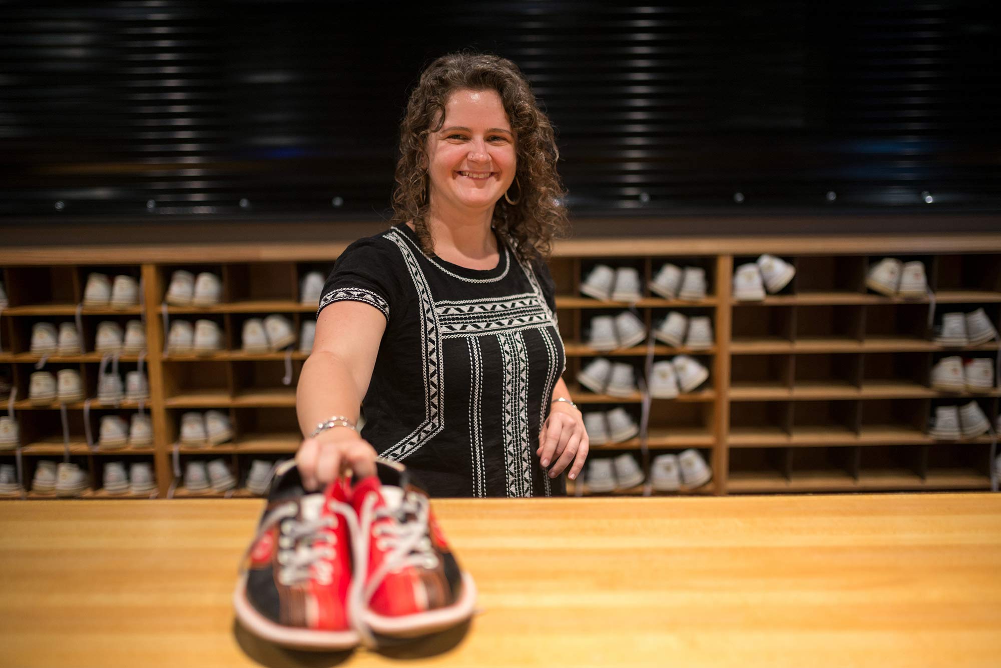 Woman giving a pair of bowling shoes to someone across a counter