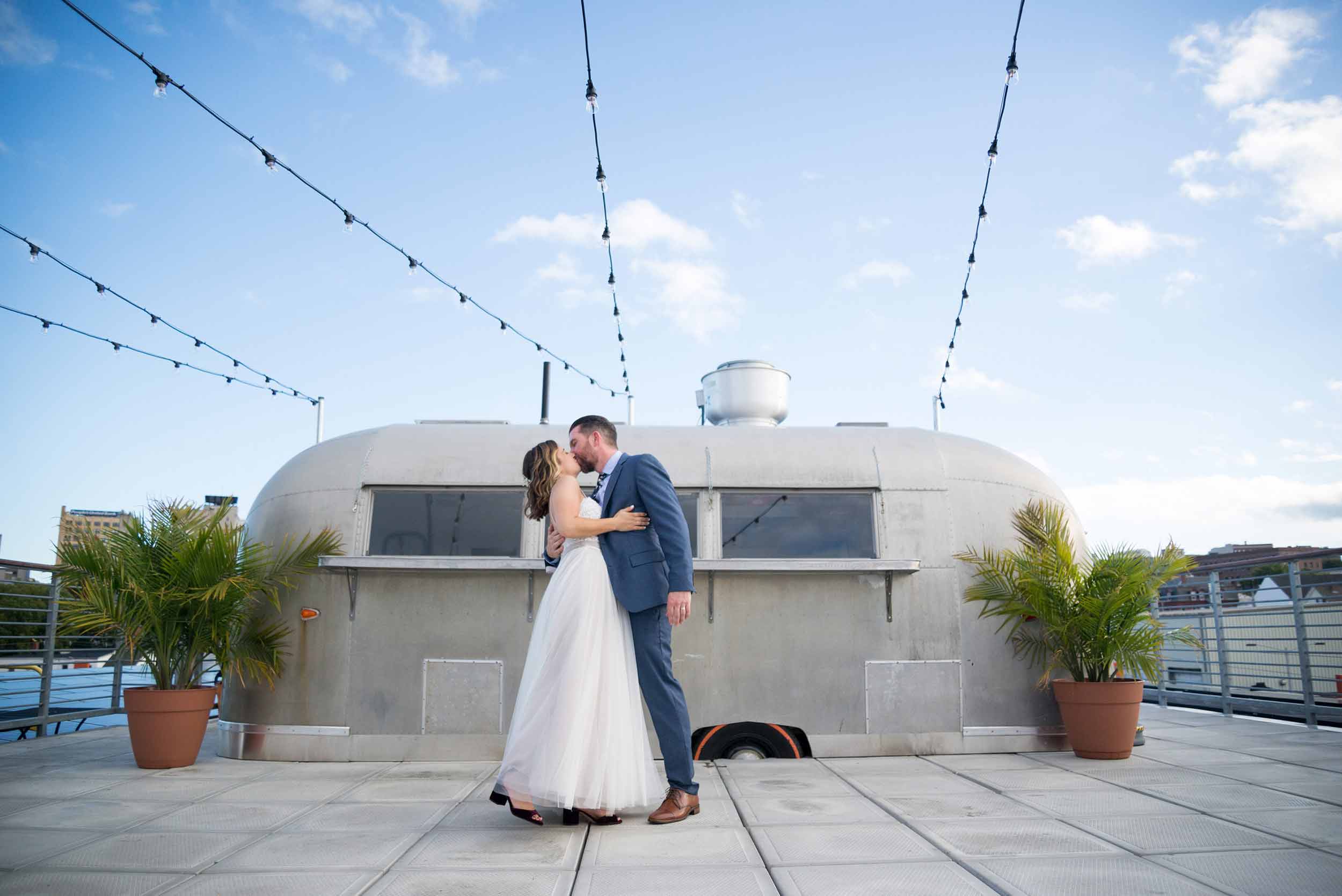 Bride and groom kissing in front of taco truck on a rooftop