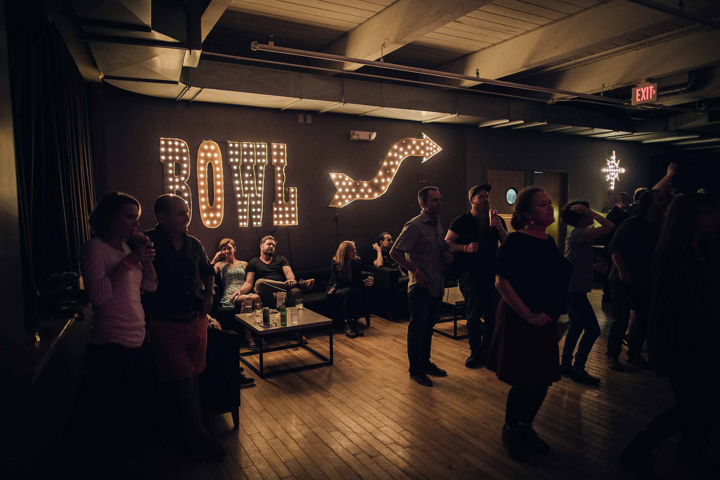 Crowd of people in front of large neon 'Bowl' sign