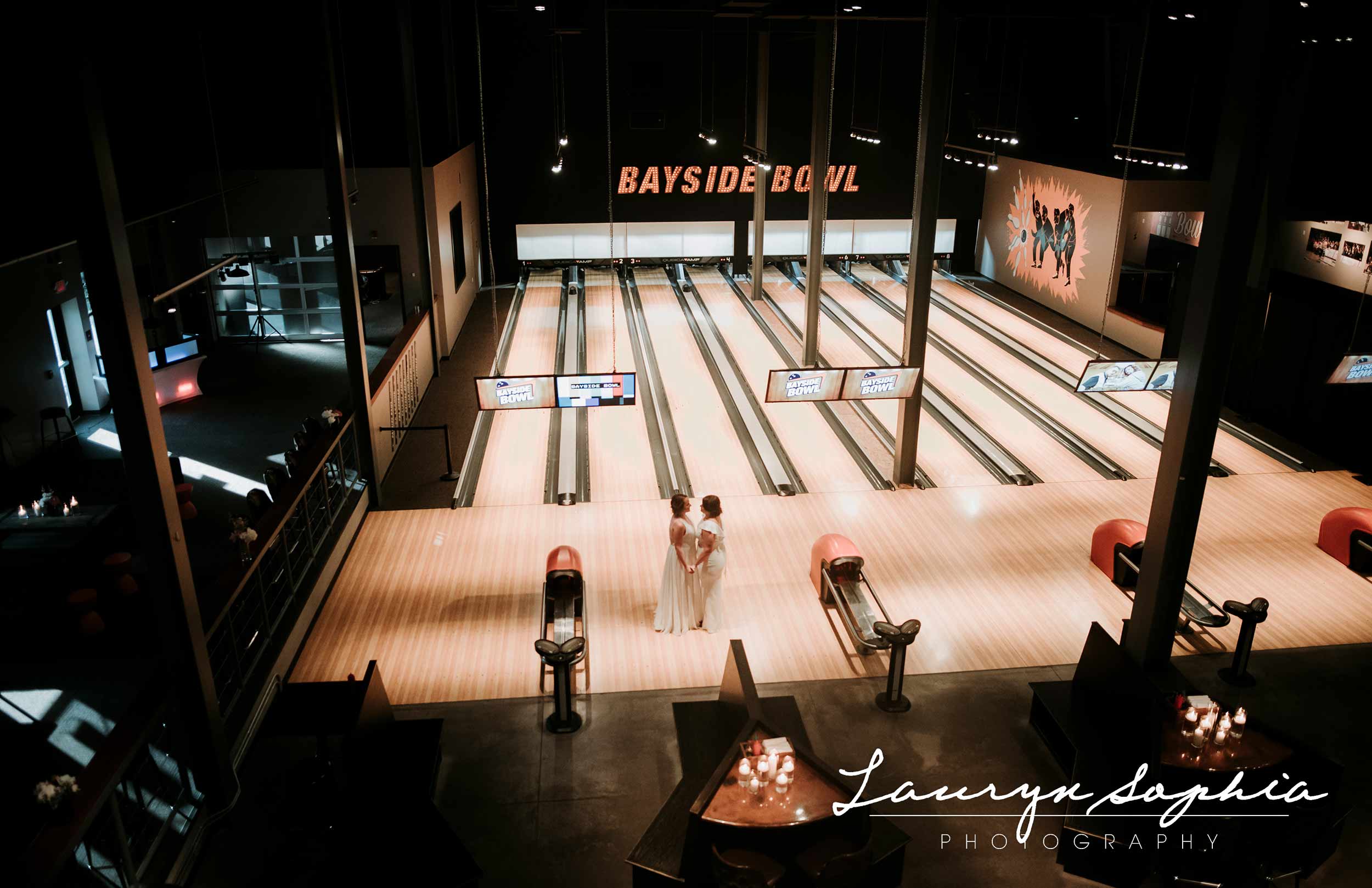 Two brides kissing on bowling lanes