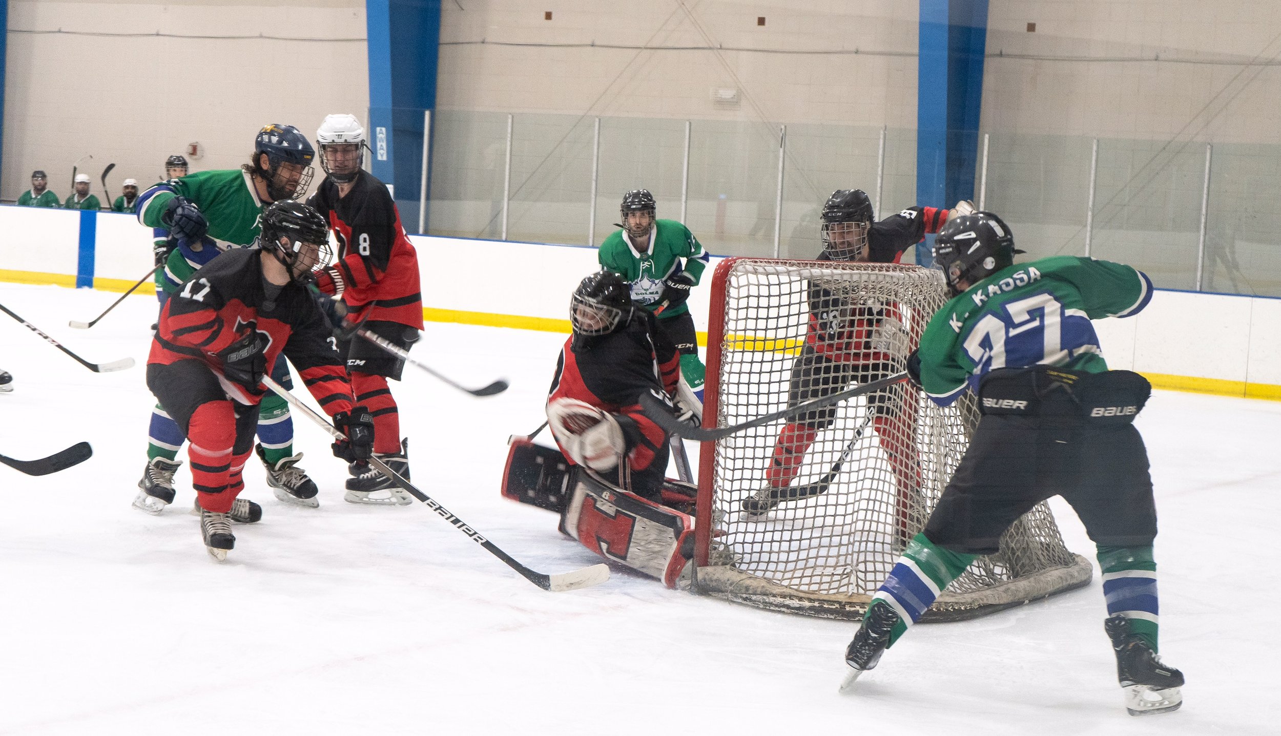  Team Red goalie Isaac Garmo makes a save on a shot by Team Green’s Brian Kassa (left) during the Chaldean Hockey League playoff championship game. 