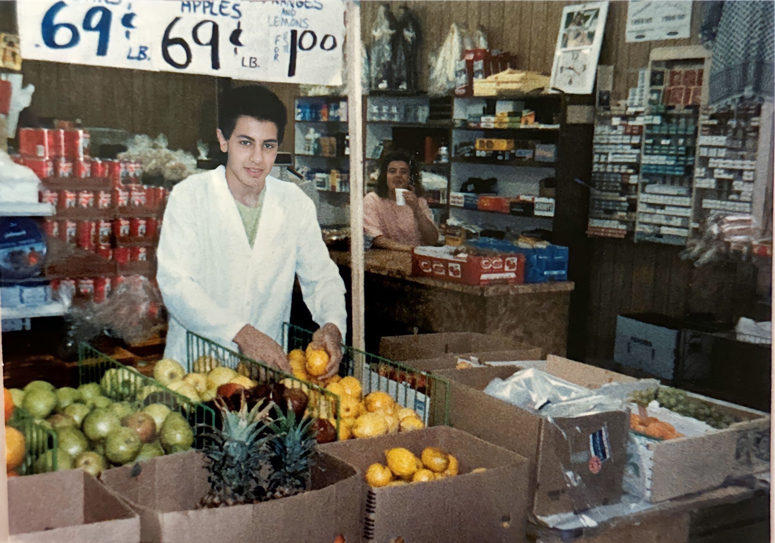  Kevin Boji arranges fruit while a cashier looks on. 