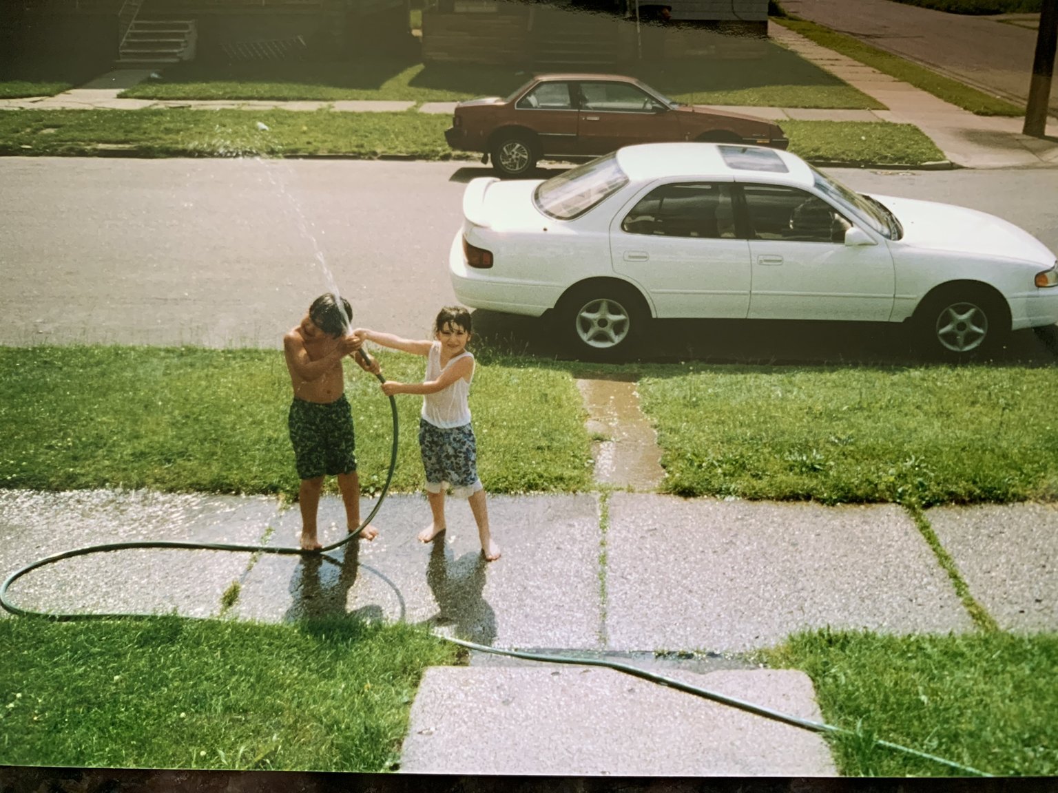  Alexa Saffar and her cousin Randy Abboud playing with the hose in the front yard 