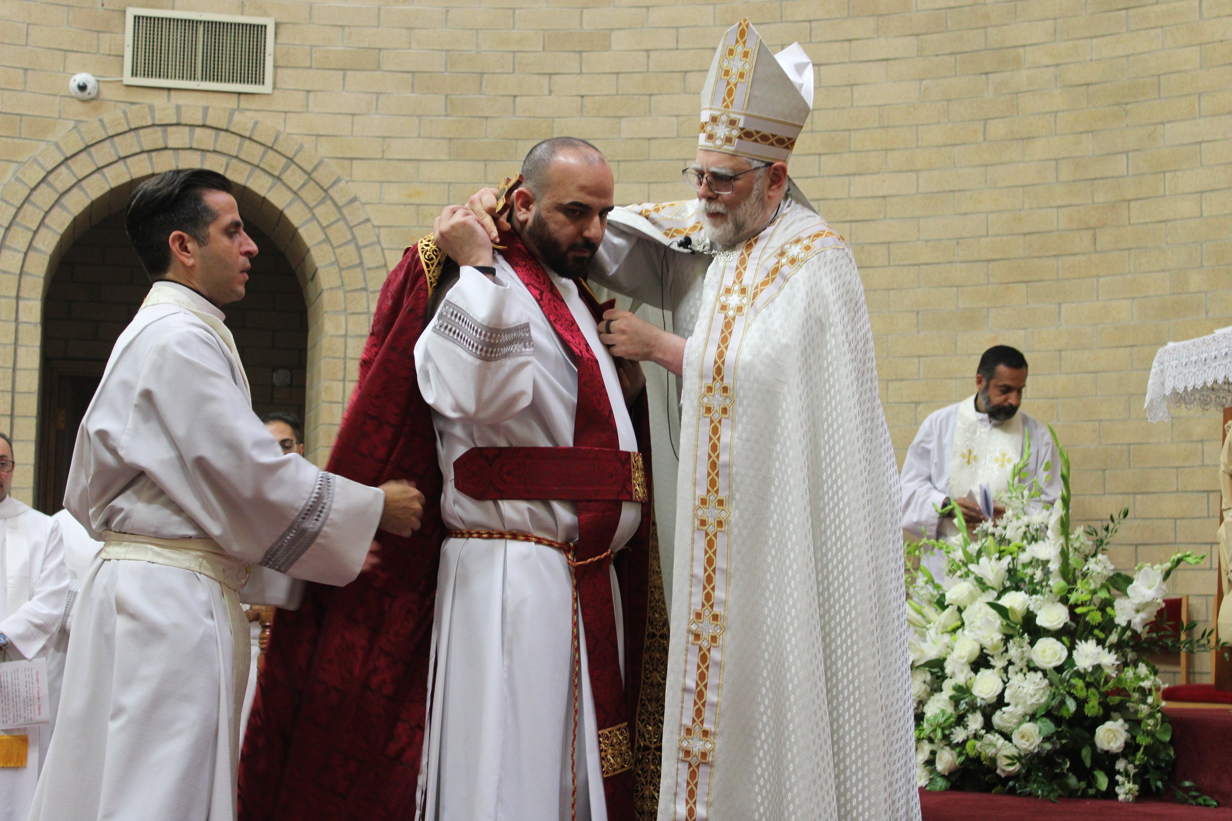  Bishop Francis placing the priest’s cope on a newly ordained Fr. Namir with help from Fr. Bryan Kassa. 