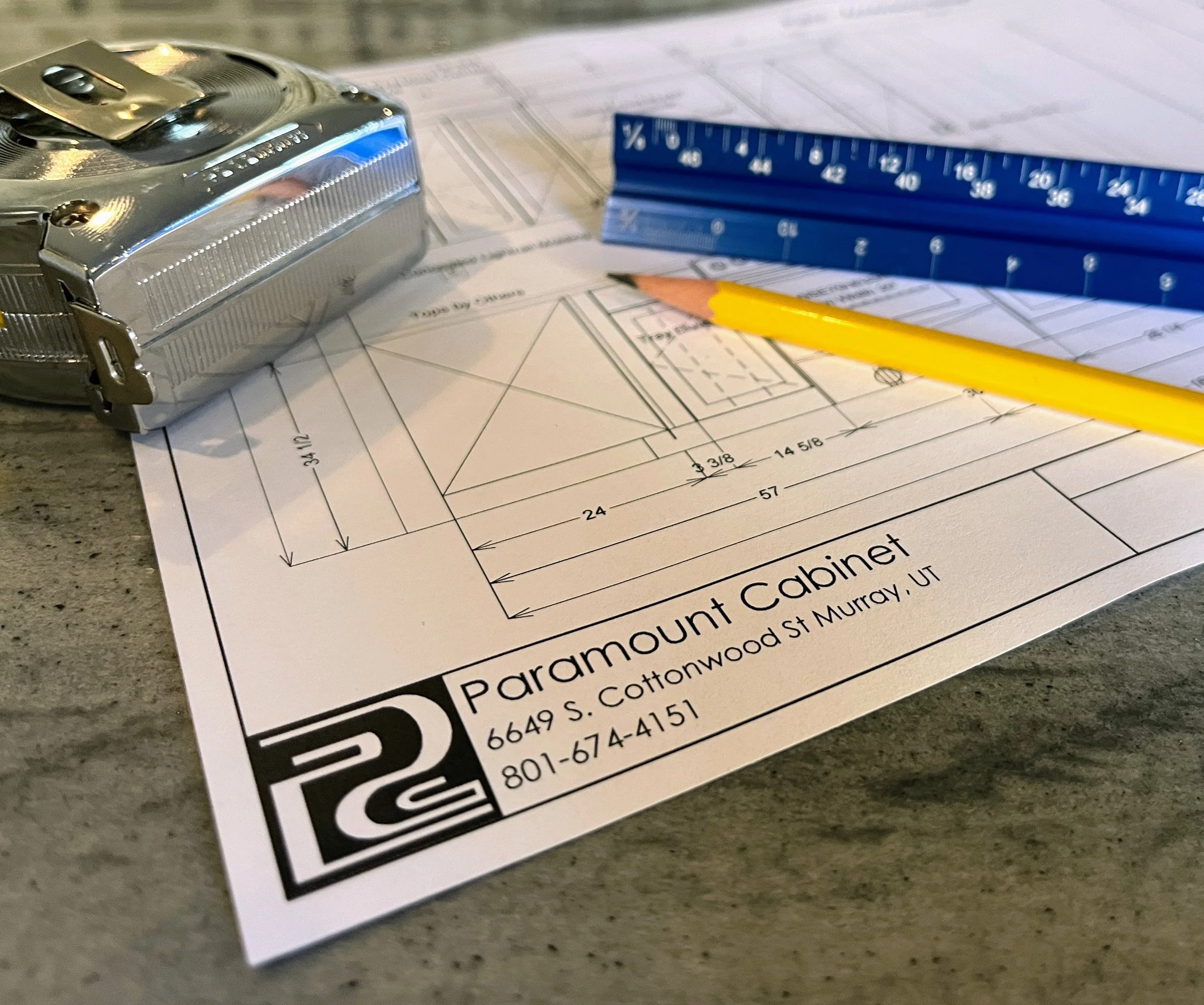 Cabinet Drawings on Paper with a tape measure, pencil, and architectural ruler on top of a granite counte top.