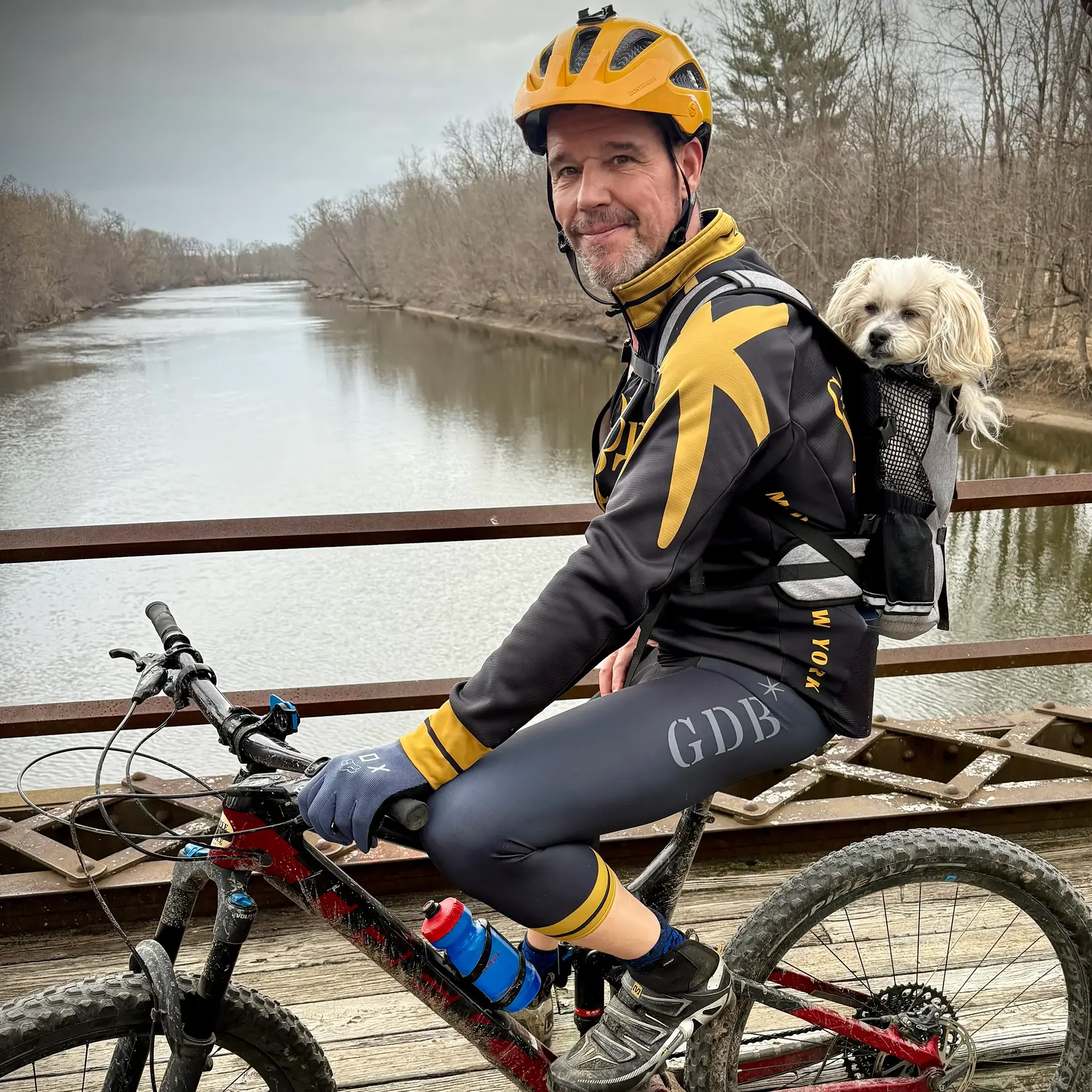Corey Carthew professional voiceover artist riding bike with Scotty the dog on bridge