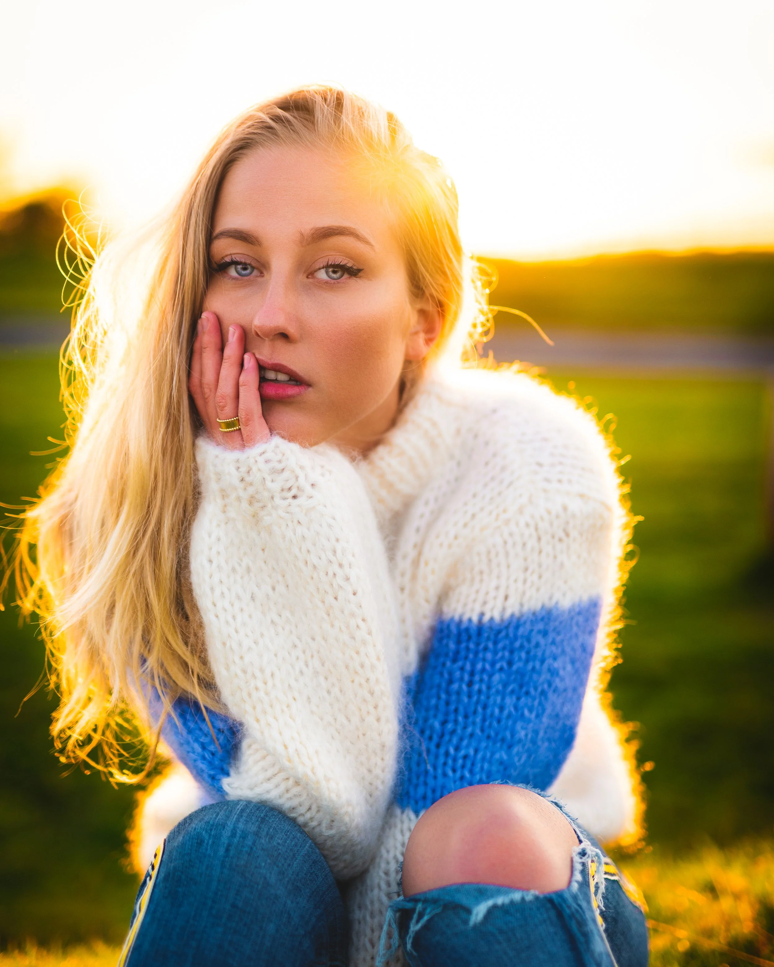 Blonde woman in white sweater seated in warm golden hour sunlight
