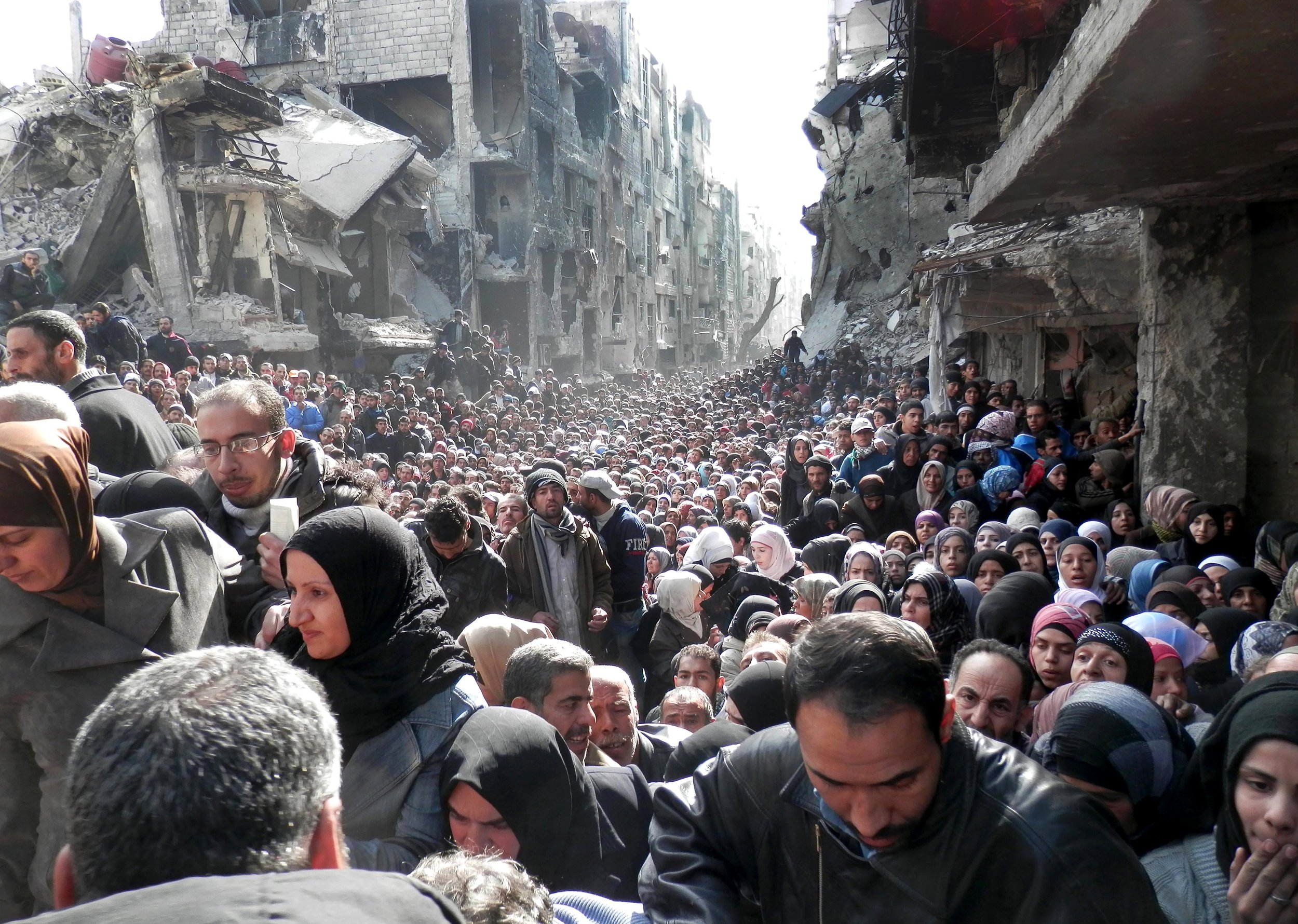  Residents of the besieged in Yarmouk line up to receive food supplies in Damascus, Syria, Jan. 31, 2014. 