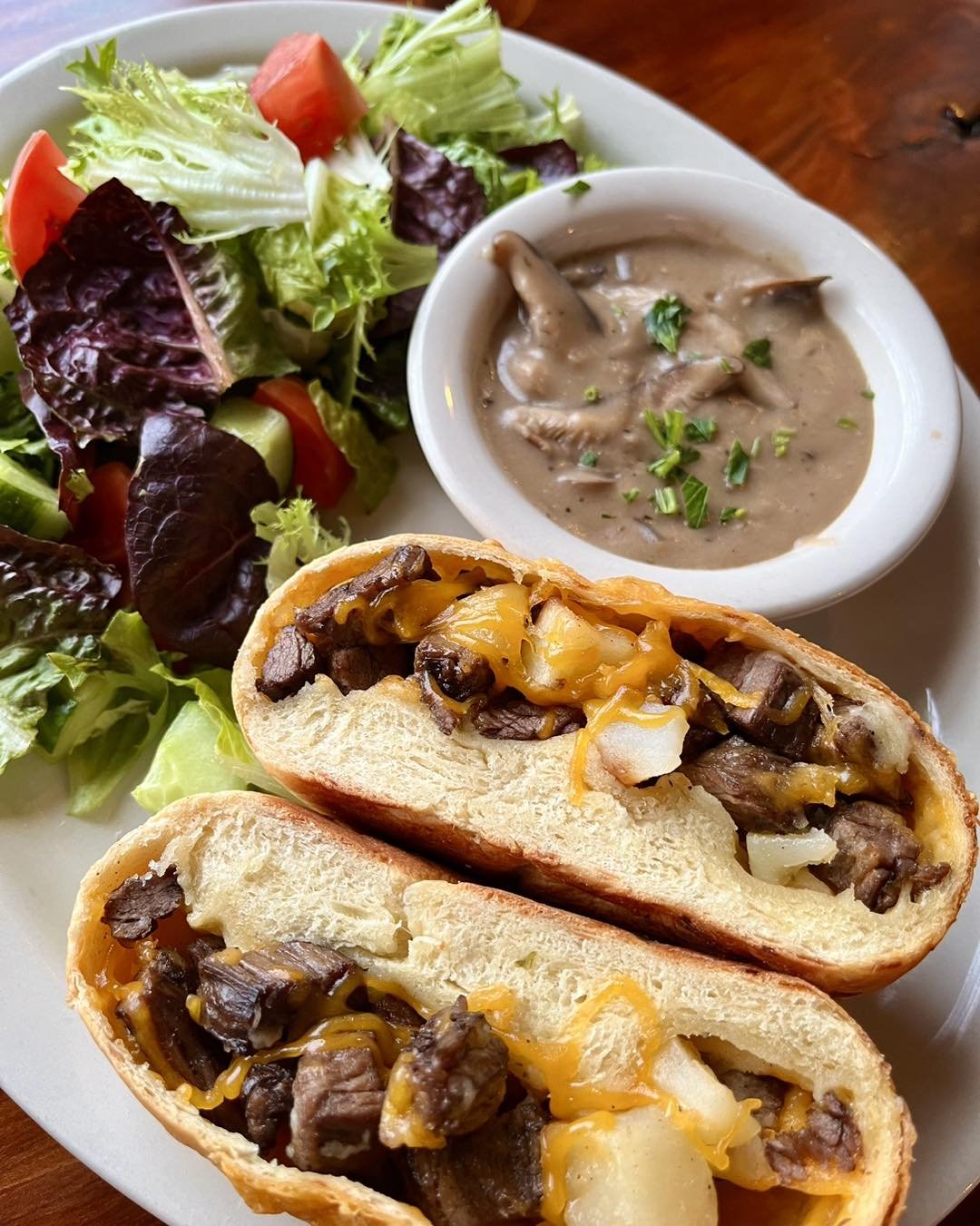 Steak Hand Pie&ndash;Skirt steak with potato, cheddar cheese &amp; green onion baked in soft parmesan bread. Served with gorgonzola mushroom gravy for dipping &amp; a green salad.