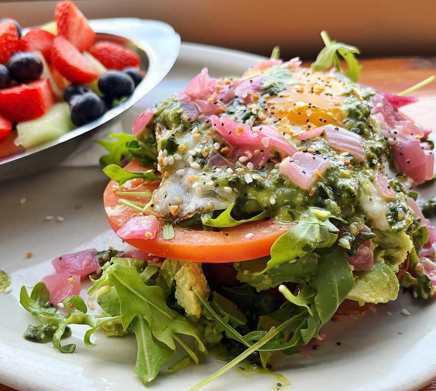 Avocado Toast is back on special for breakfast! 🥑 Toasted wheat bread topped with avocado, arugula, tomato, fried egg, basil vinaigrette, pickled red onion &amp; everything bagel seasoning, served with fresh fruit.