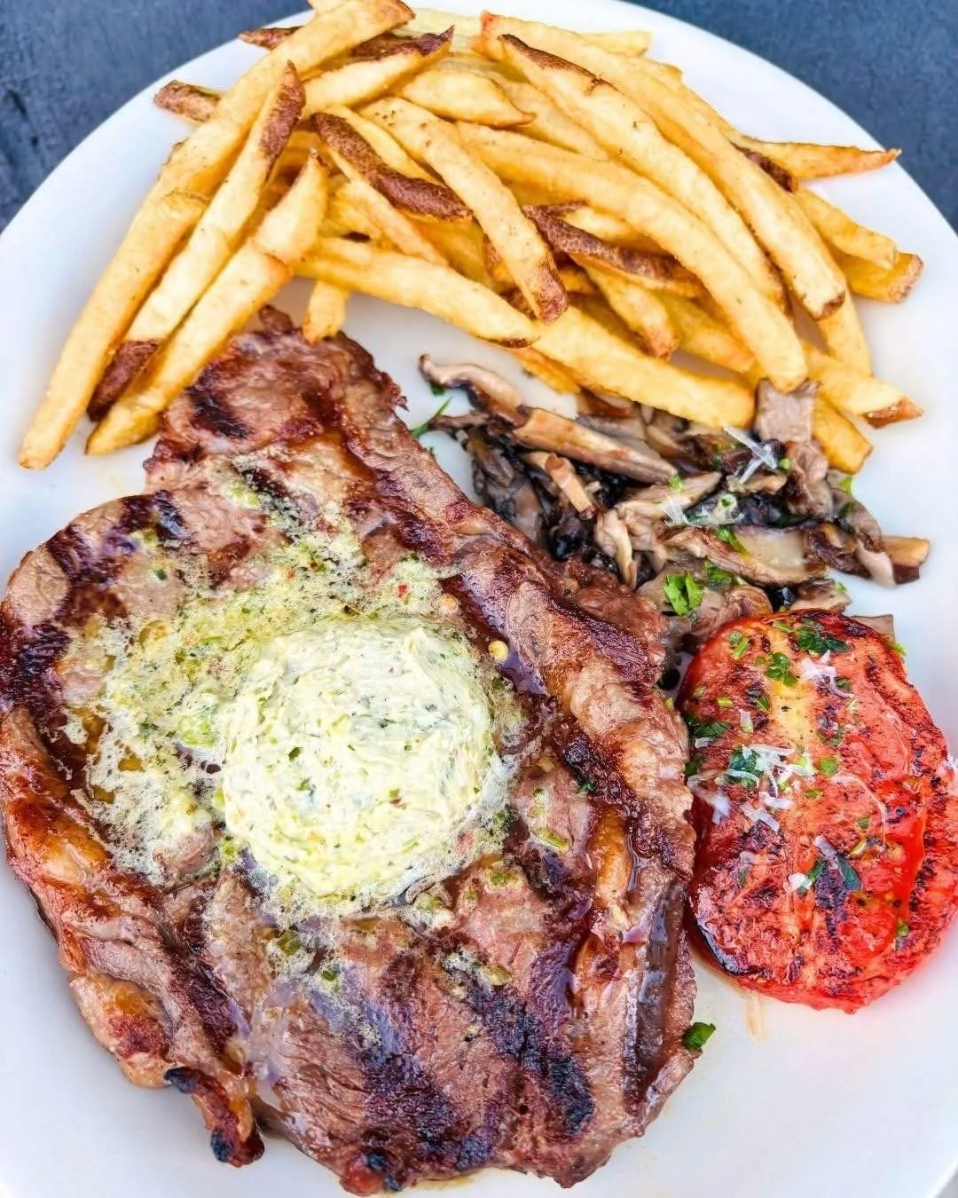 Last day for Steak Frites! Come in for dinner tonight. A 10 oz Ribeye seared medium and topped with parmesan chimichurri butter. Served with fries, roasted tomato and sauteed wild mushrooms, $33.00.