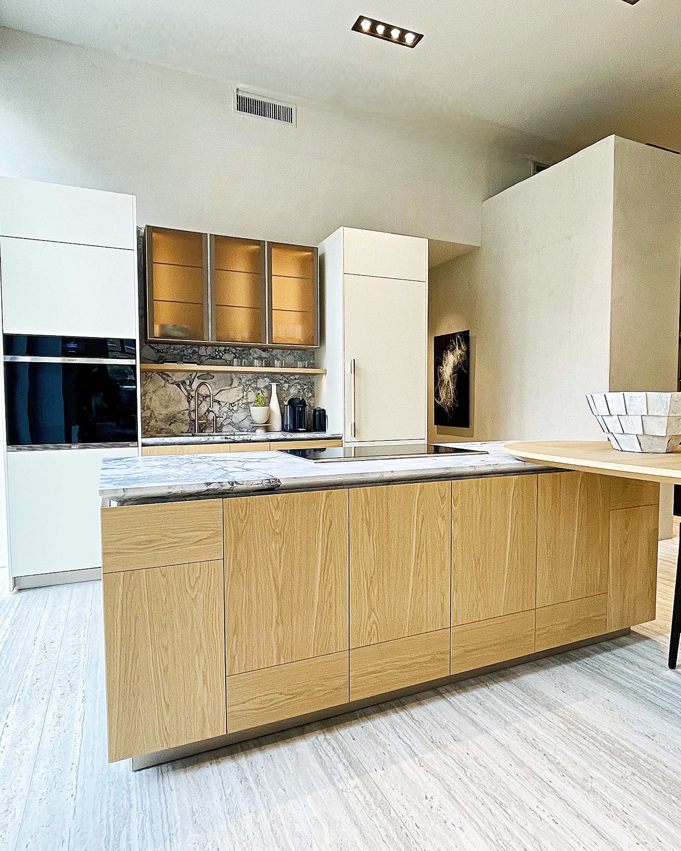 This Boynton Beach luxury Italian kitchen custom made in European light oak wood has a two tone painted and natural finish with glass front wall cabinets and striking countertops.