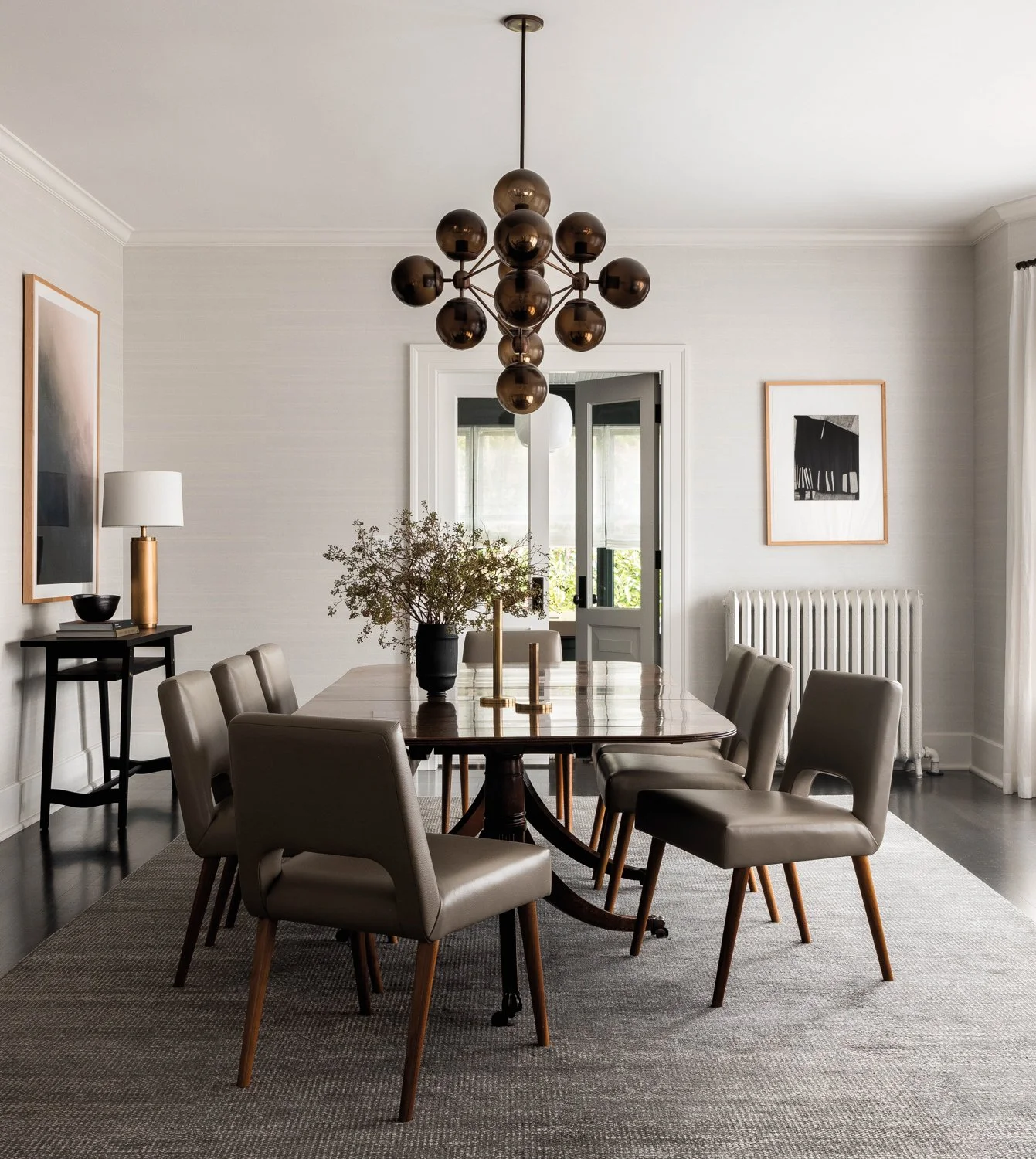 Timeless Palm Beach luxury dining room with modern chandelier, timeless dark wood table and leather modern chairs, all in neutral colors.