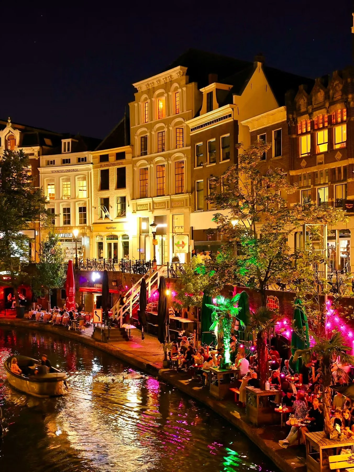 The Utrecht canal lights up the architecture at night, bustling with action on a warm night.