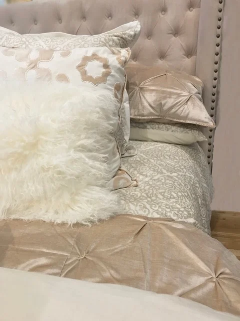 home styling in delray beach of a luxurious bed with a mix of textured champagne and white linens