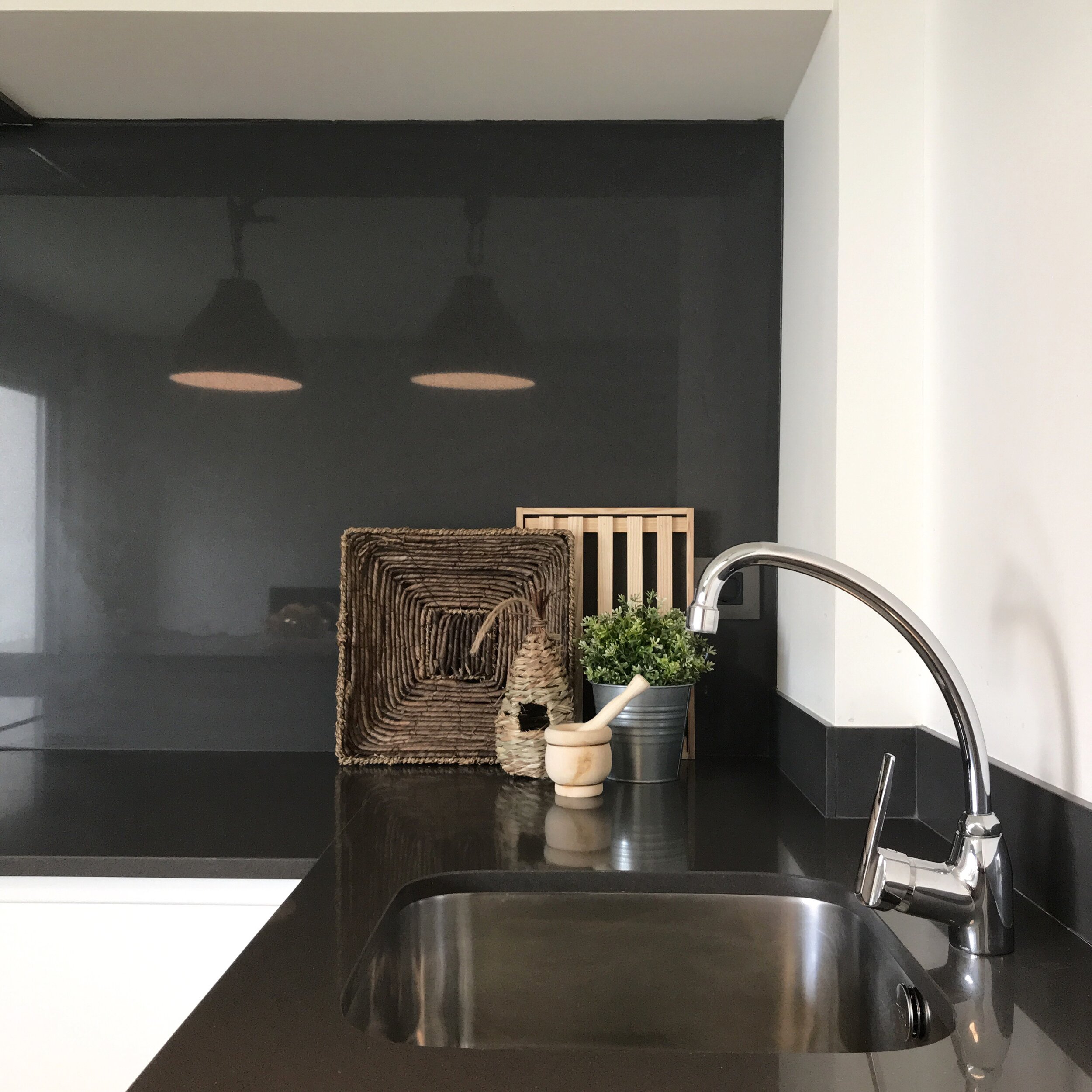 Image of a dark gray kitchen counter with stainless sink elegantly turns into the eating area.