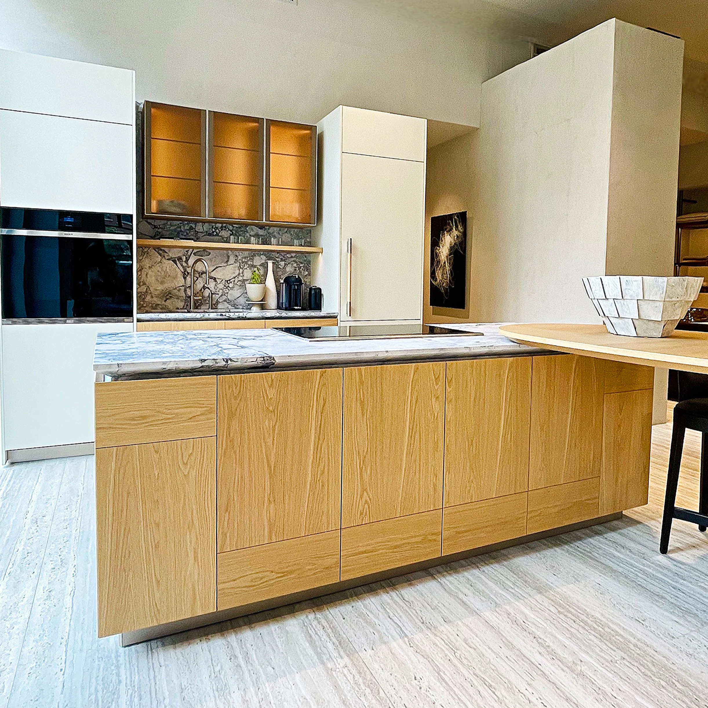 This Palm Beach modern kitchen is in painted cabinetry with rich Italian Oak. The warm and neutral color palette feels effortless. A striking island shows an unusual edge detail on the marble countertops.