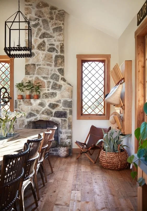 European-inspired dining room with a stone fireplace, woven chairs, leaded-glass windows, and wood floors helps support rhythms.