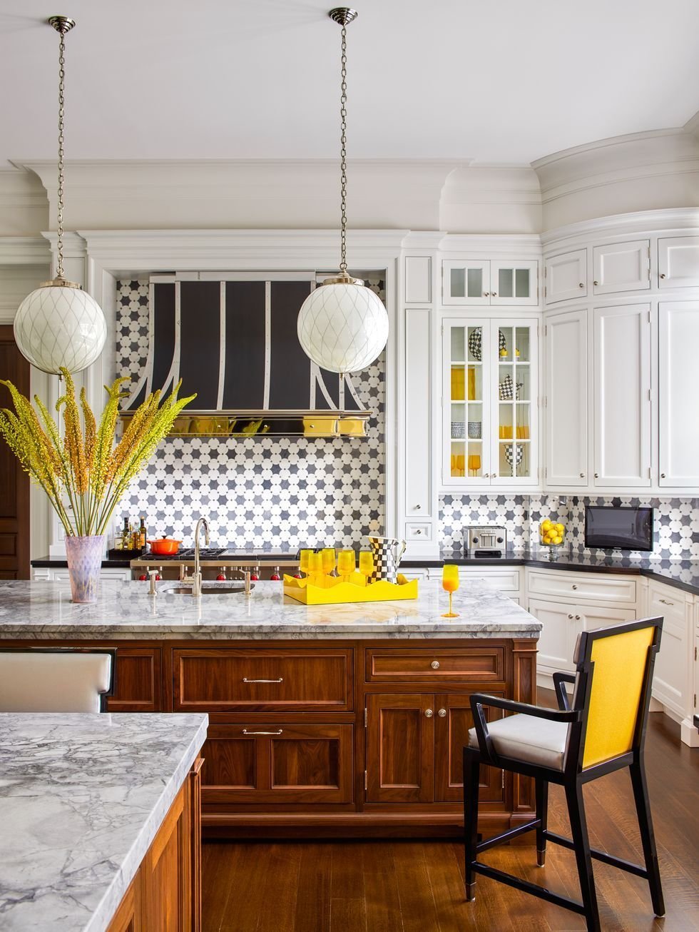 Palm Beach luxury kitchen design with white cabinetry, wood island, geometric tile backsplash, marble counters, and yellow accents.