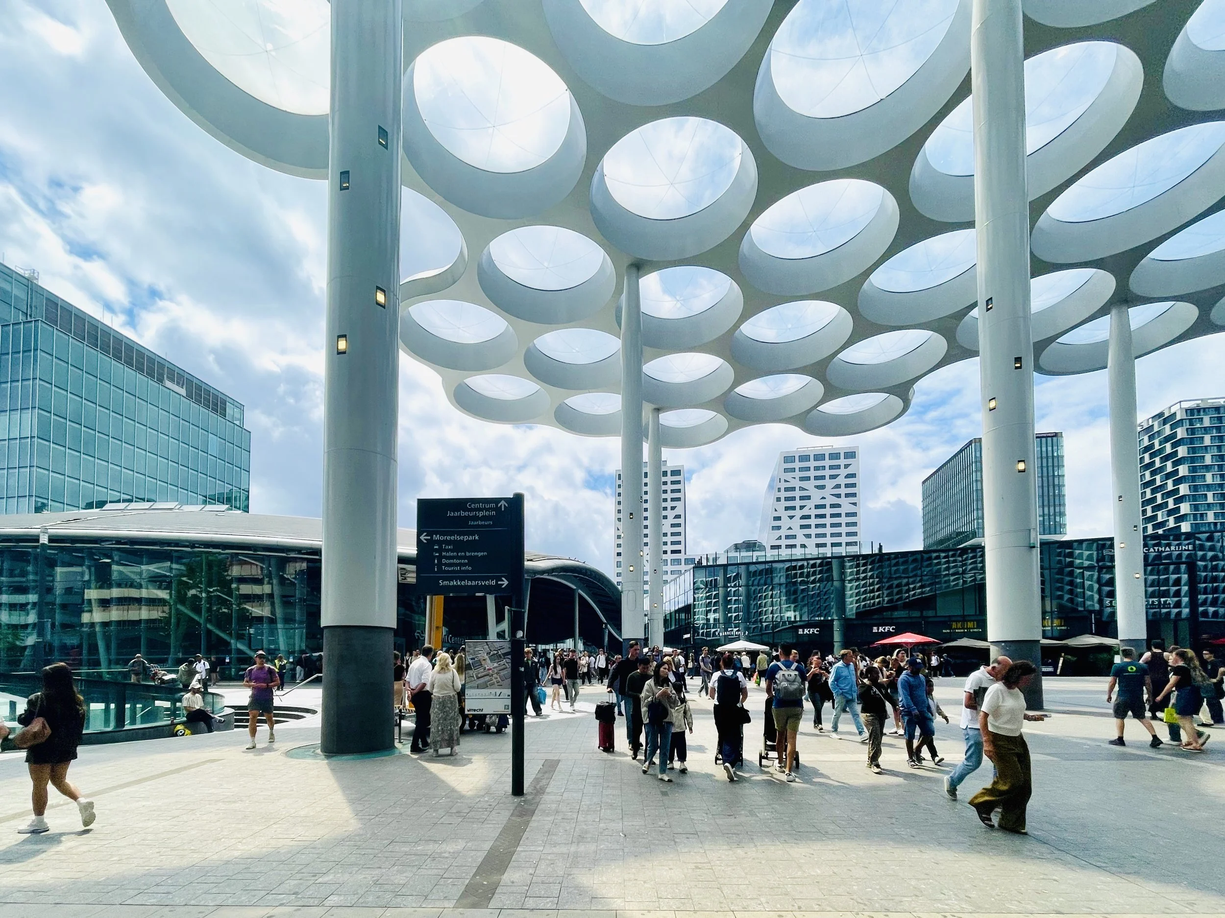 The Utrecht train station exit has a modern, white canopy structure overhead upon exit.