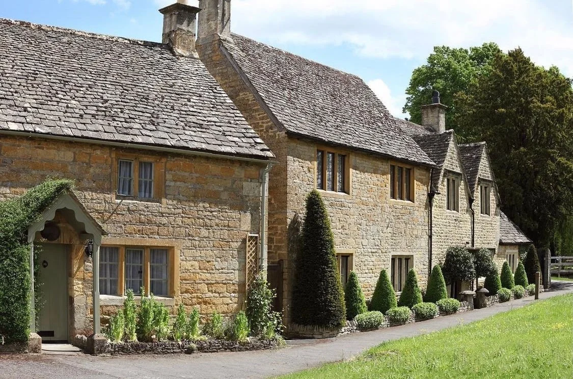 English countryside stone cottage surrounded by garden greenery and natural landscaping.