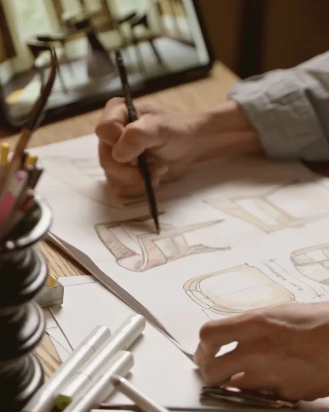 Interior designer draws custom furniture including dining chairs, with photo of the proposed dining set in the background. .