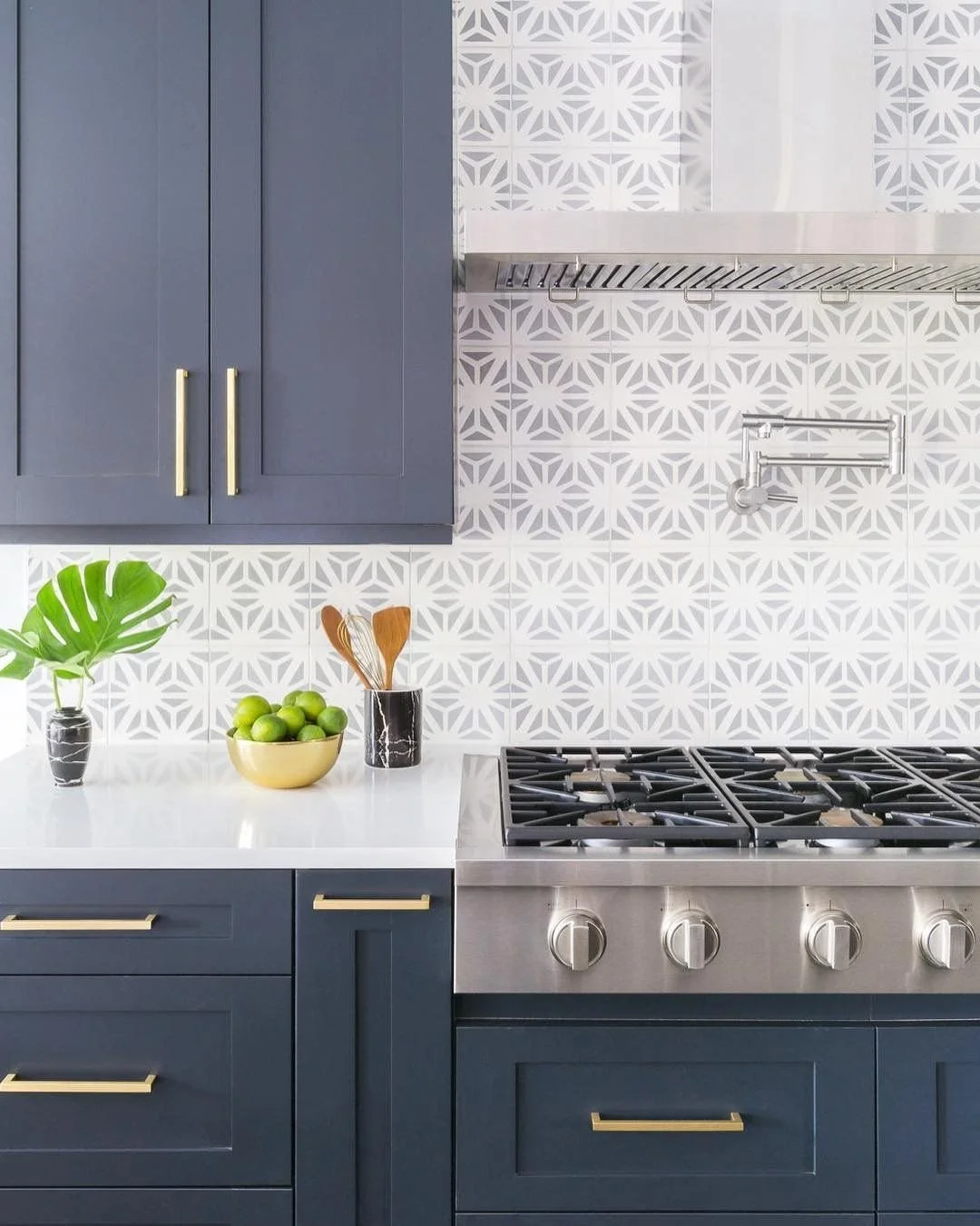 Palm Beach modern kitchen design by Domaine Luxe with navy cabinetry, brass pulls, white quartz countertops, stainless range, and patterned geometric backsplash.