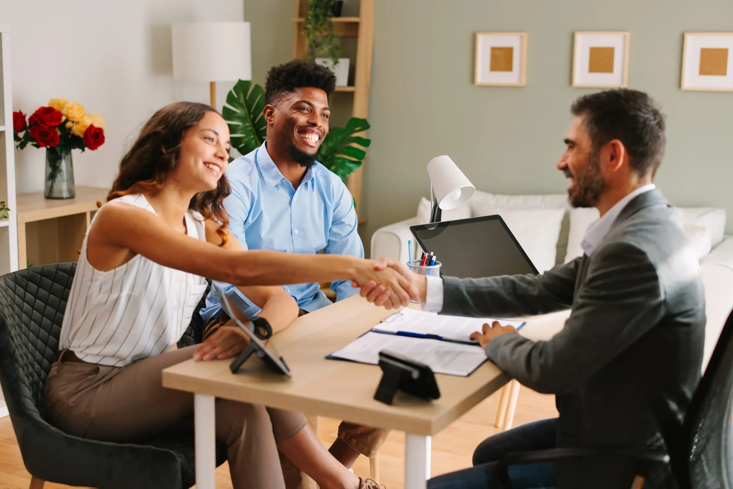 Homebuyers shaking hands with real estate agent in modern office