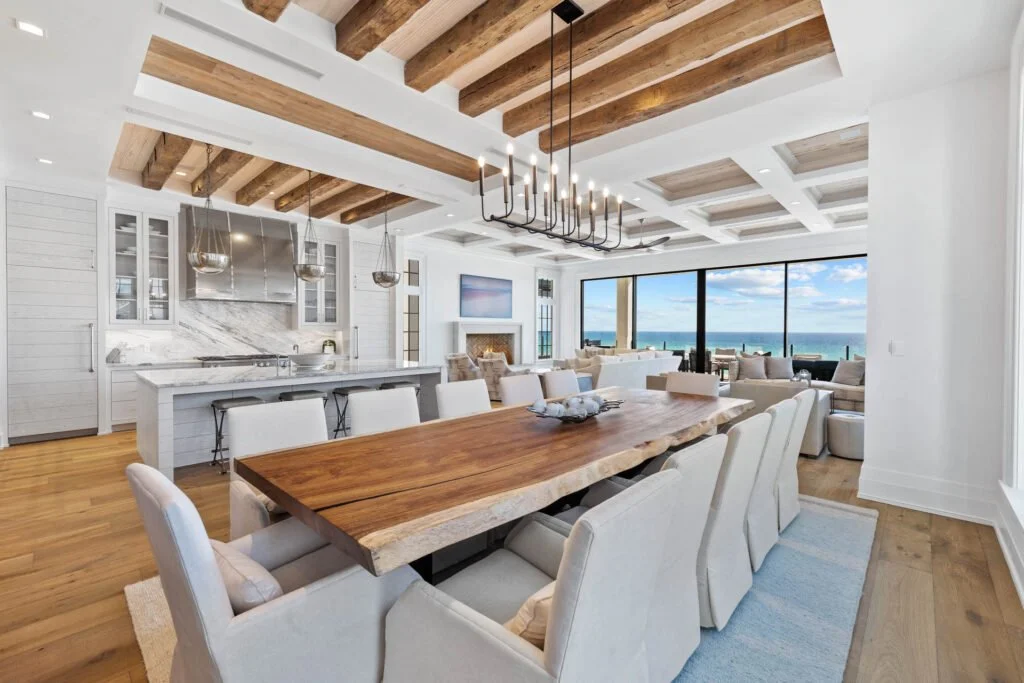 Coastal open kitchen and dining with live-edge table, linen slipcover chairs, and ocean view.